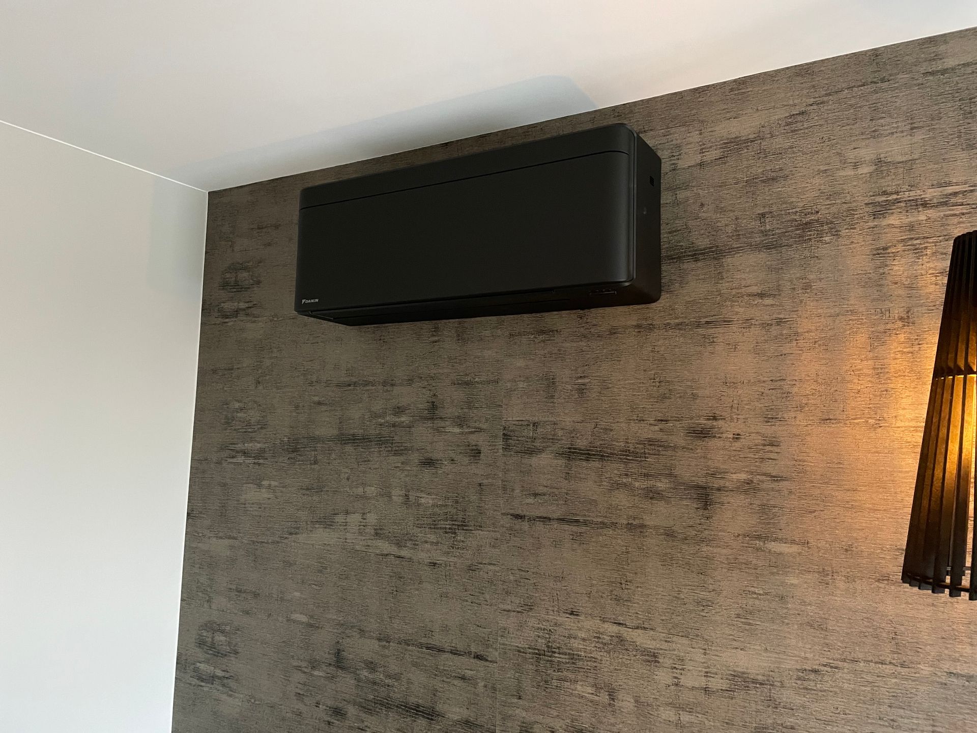 Er hangt een zwarte doos aan de muur naast een lamp.