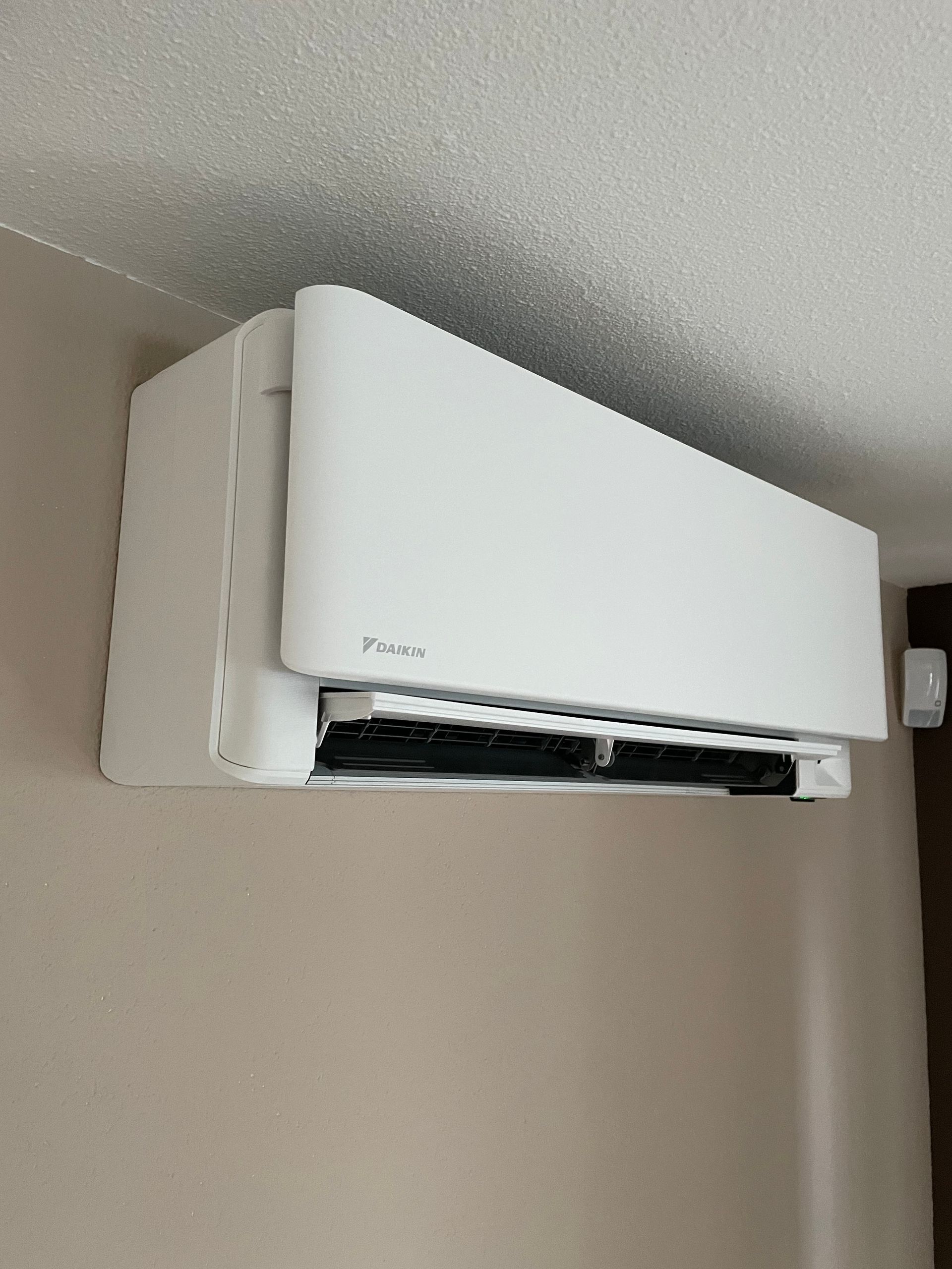 Een witte airconditioner hangt aan het plafond in een kamer.