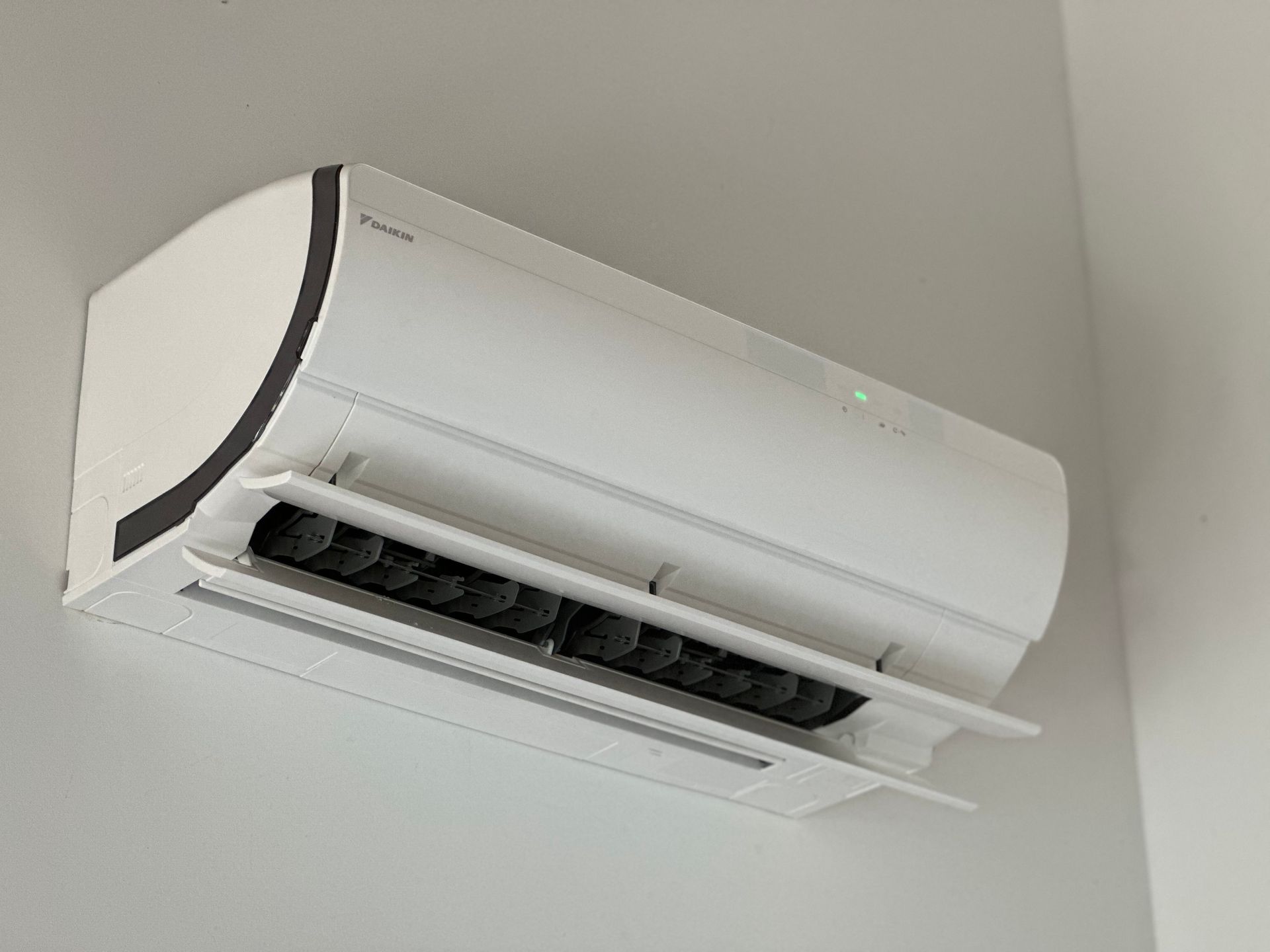 Een witte airconditioner hangt aan een witte muur.