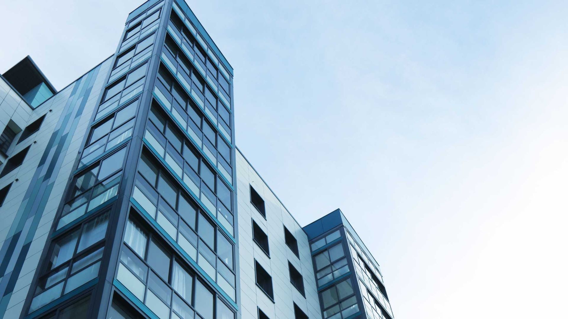 A large apartment building with lots of balconies and windows.