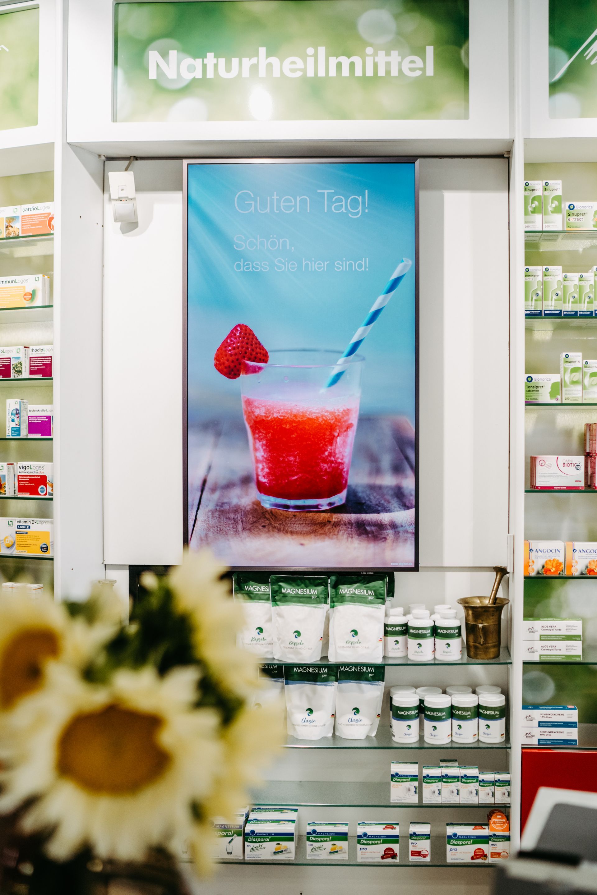 Eine Präsentation eines Erdbeer-Smoothies in einem Glas mit Strohhalm in einer Apotheke.