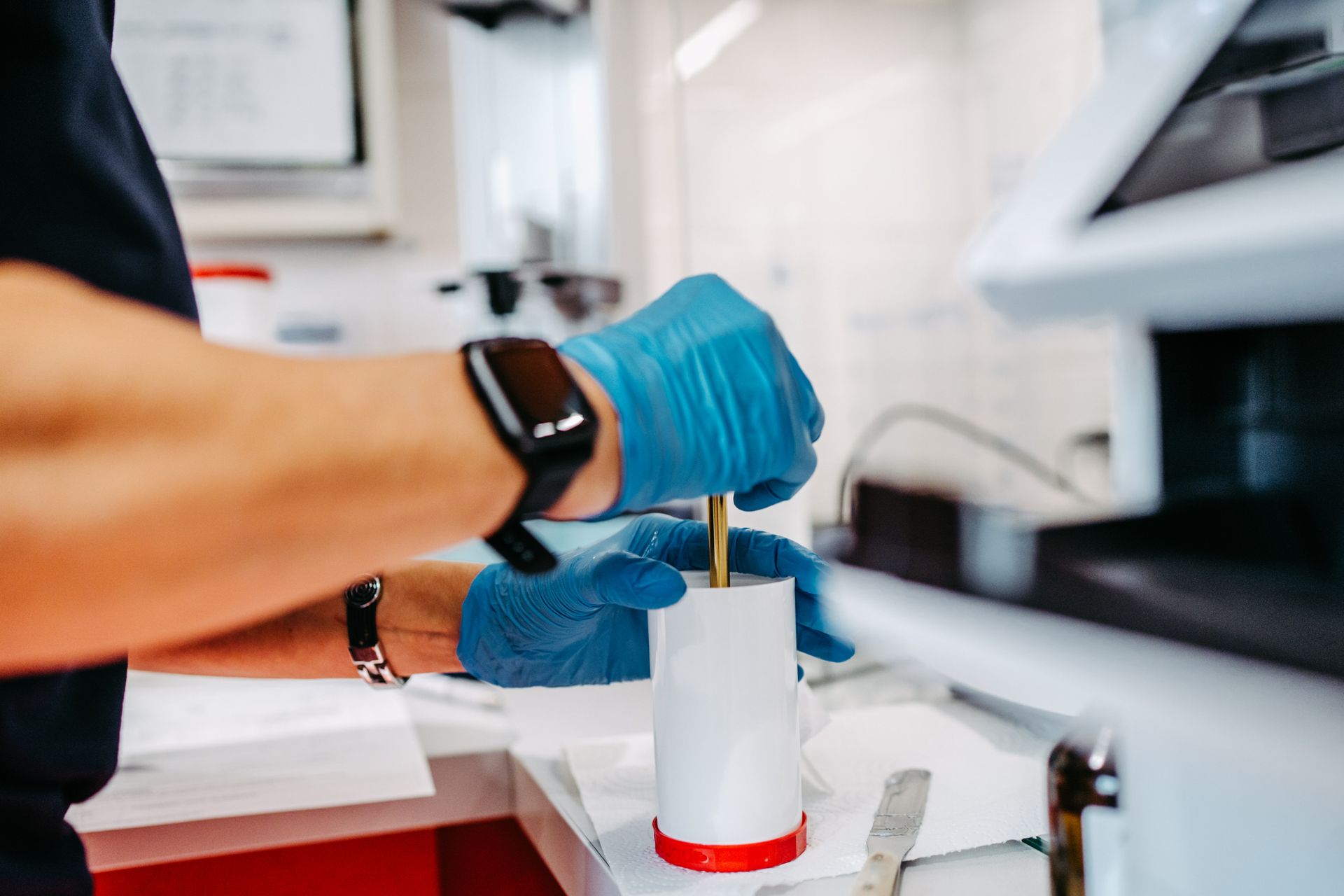 Eine Person mit blauen Handschuhen hält eine Tube mit einer Nadel darin.