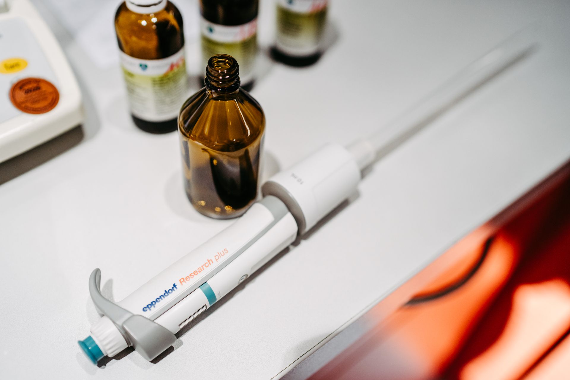 Auf einem Tisch steht eine Pipette neben Flaschen mit Flüssigkeit.