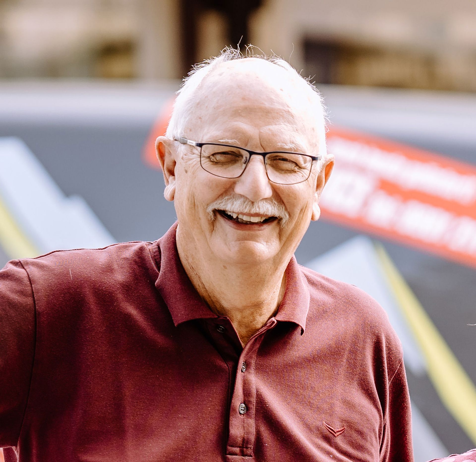 Ein Mann mit Brille und Schnurrbart lächelt in die Kamera.