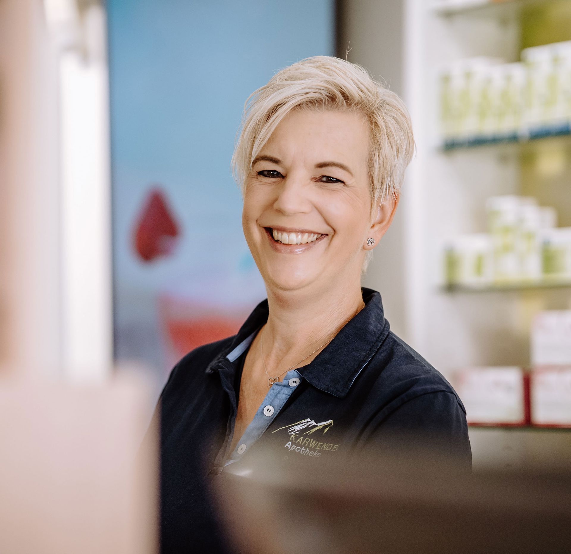 Eine Frau in einem blauen Hemd lächelt in einem Geschäft.