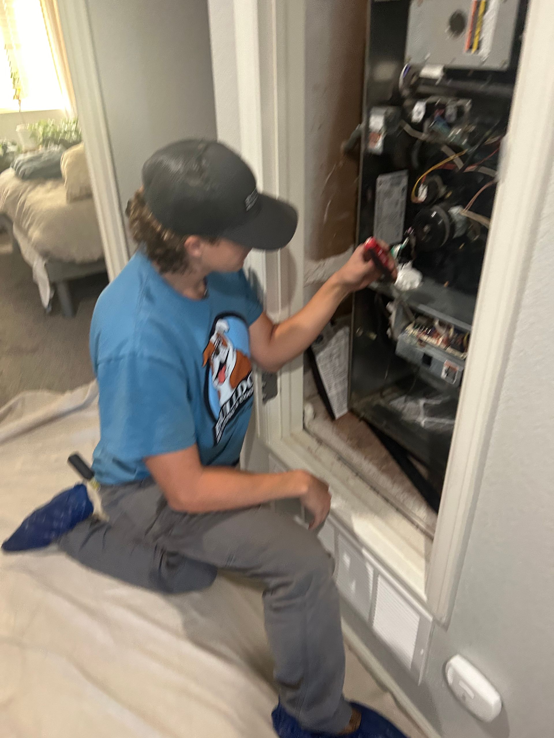 A man in a blue shirt is working on an air conditioner.