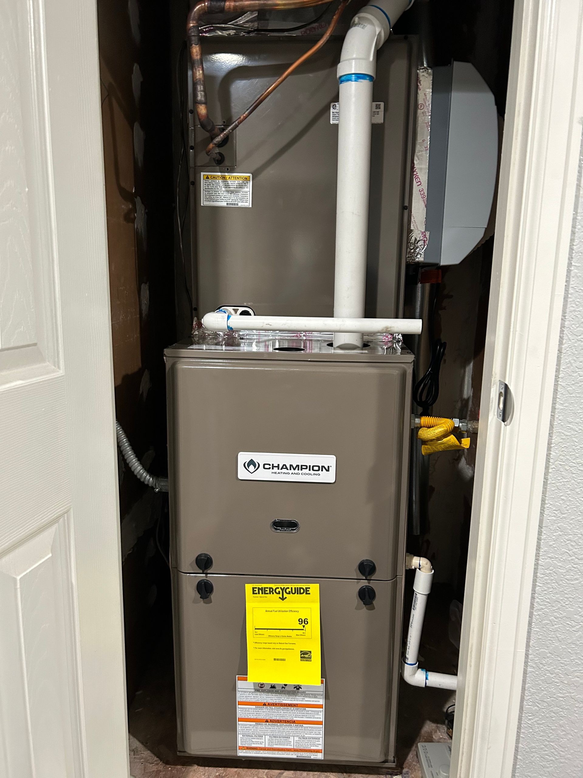 A furnace is sitting in a closet next to a door.