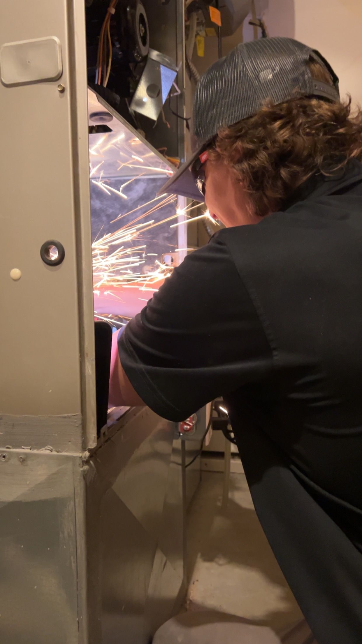 A man in a hat is working on a refrigerator.
