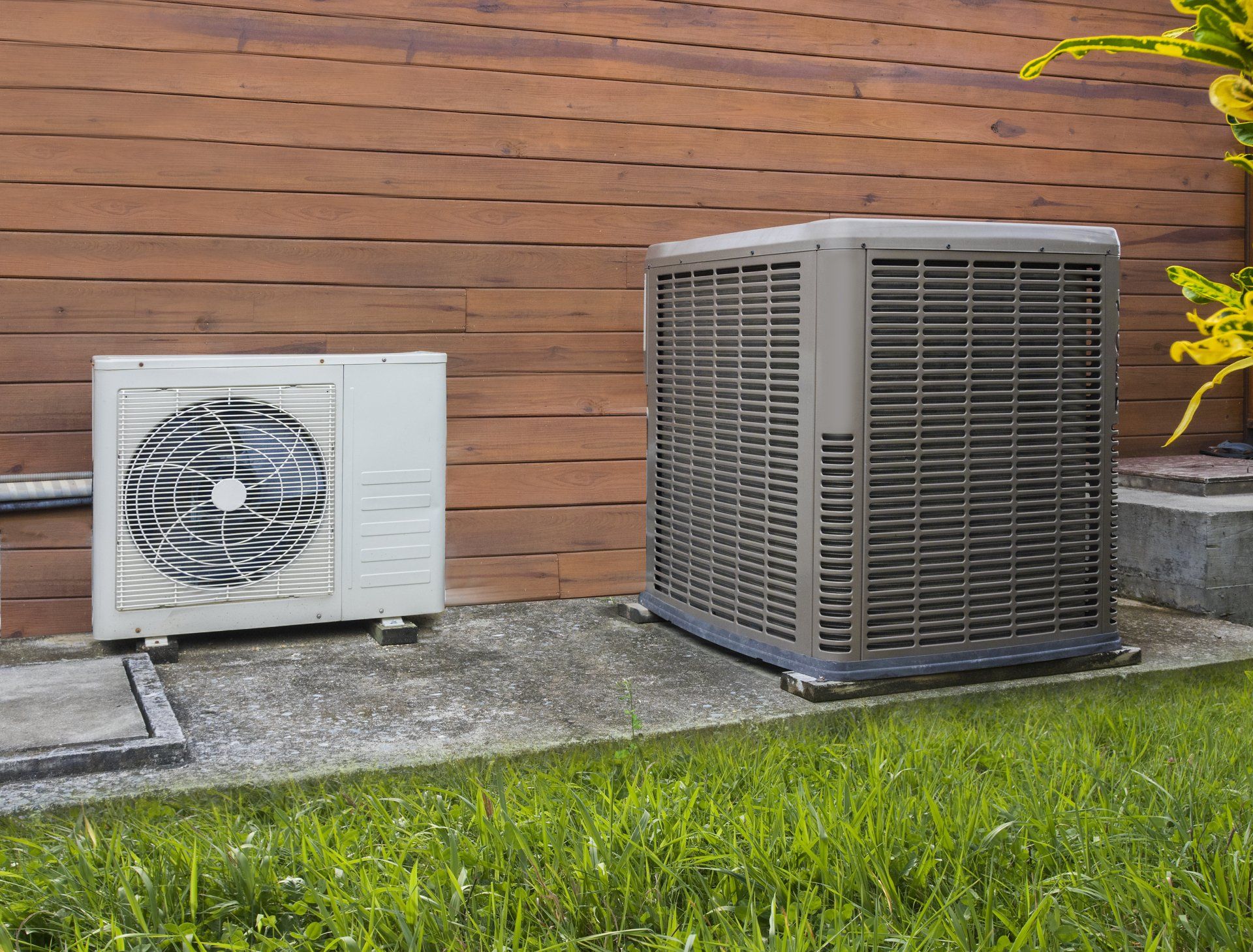 2 hvac systems next to a patch of green grass