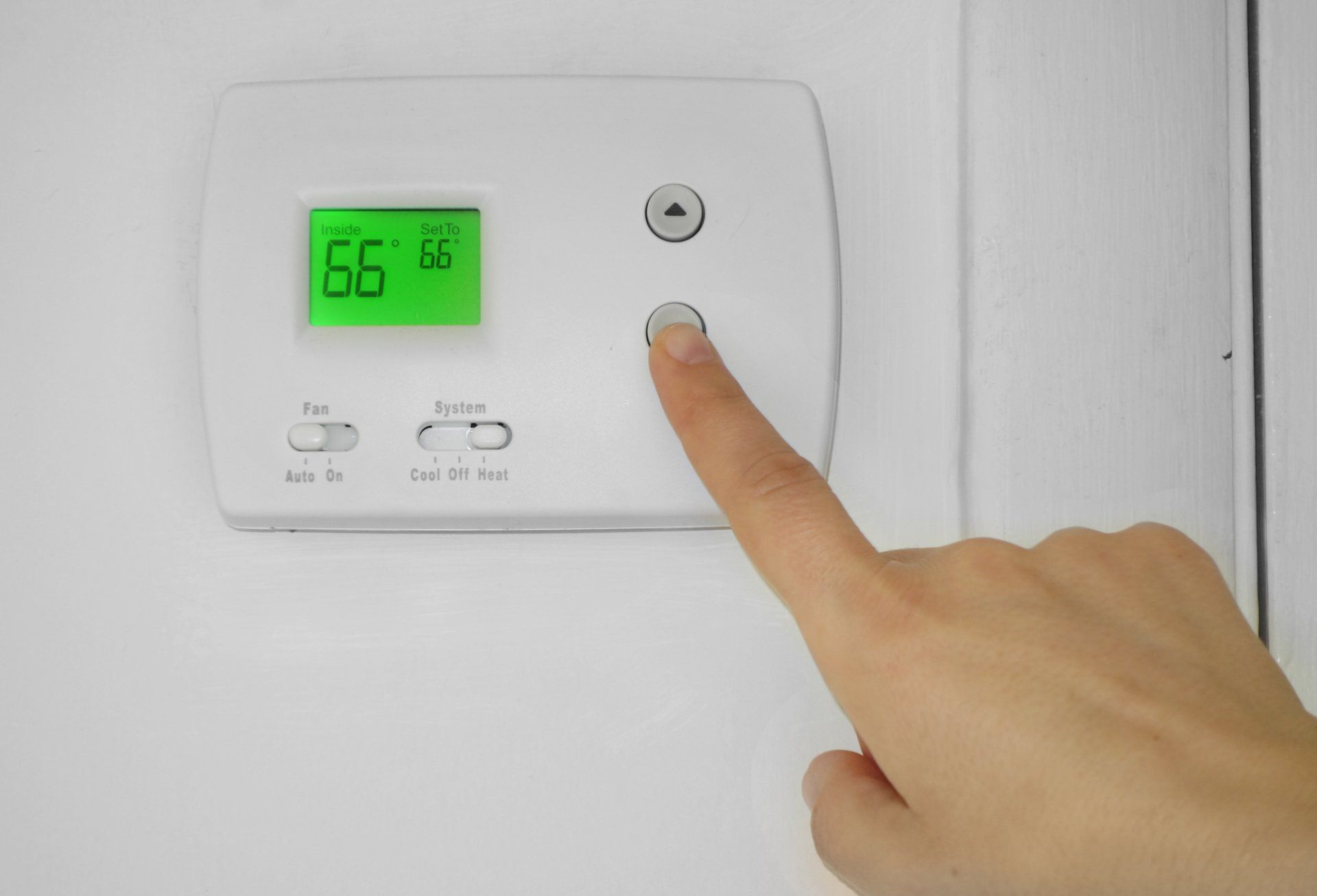 person adjusting thermostat with finger