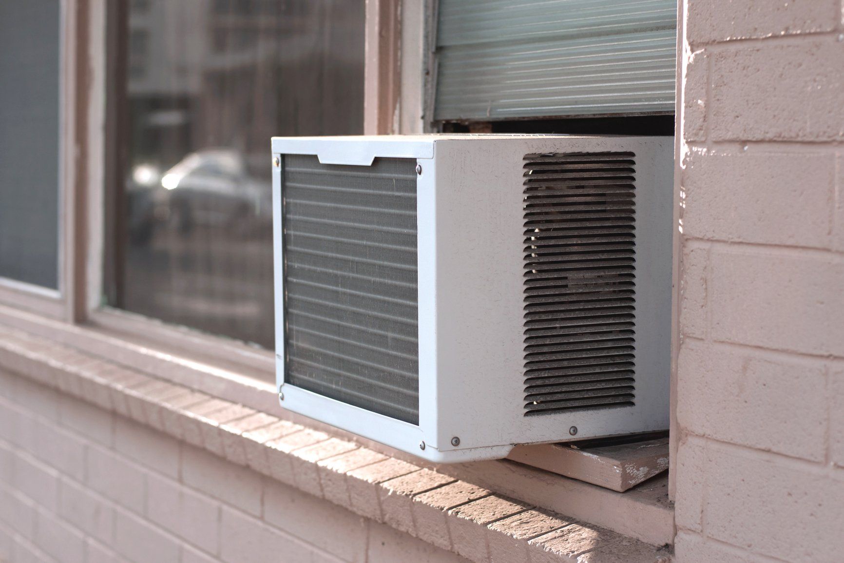 window ac unit hanging from brick building