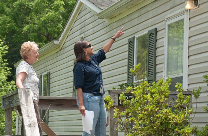 woman pointing at house while completing a home inspection with an elderly woman