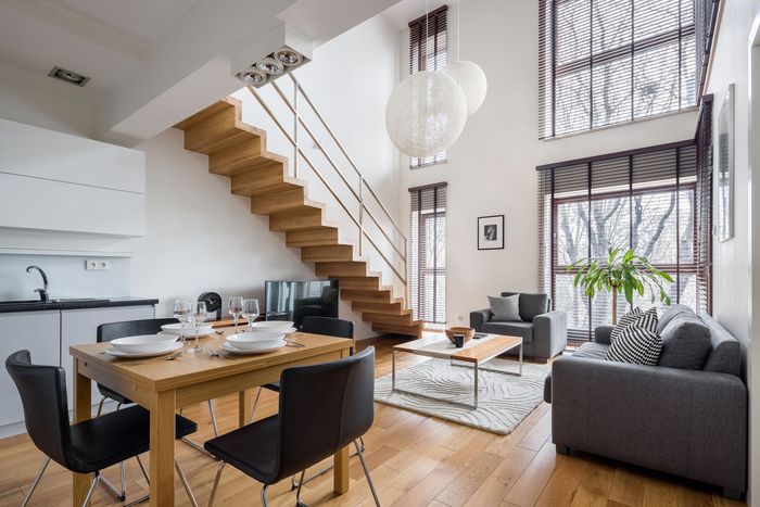 A living room with a dining table and chairs and a wooden staircase.
