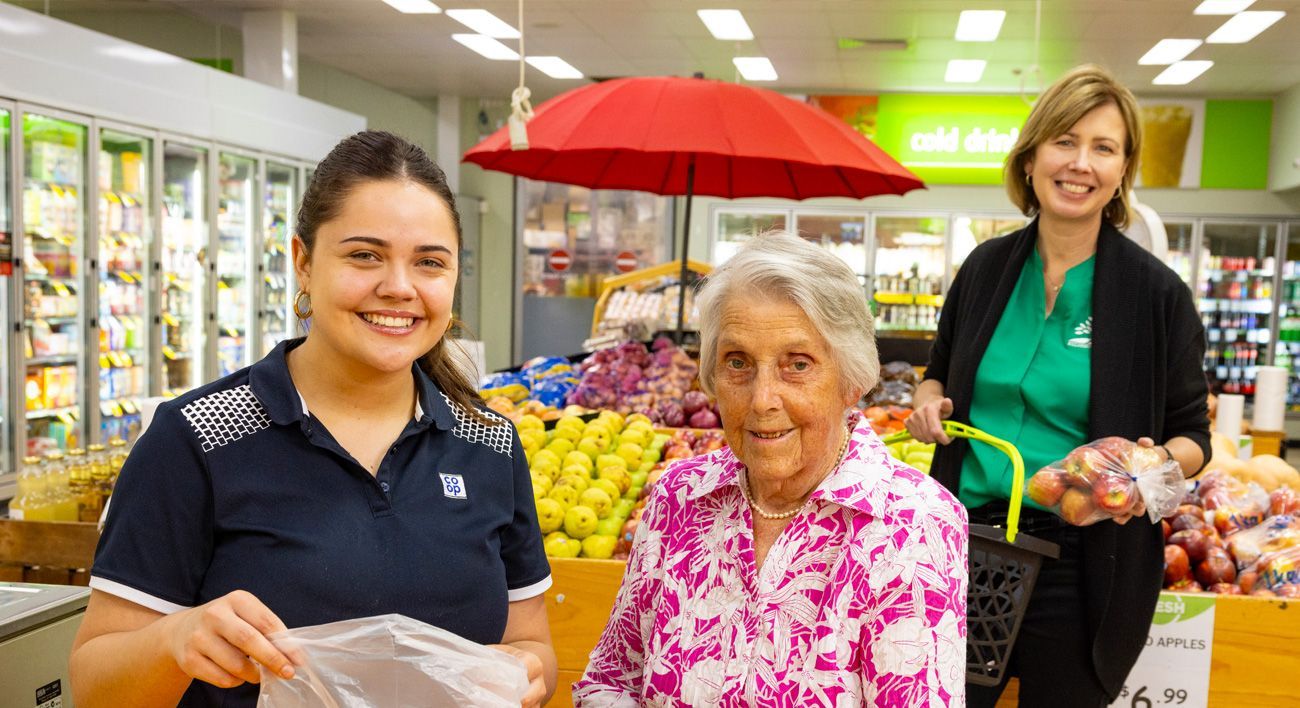 Three women are standing next to each other in a grocery store.