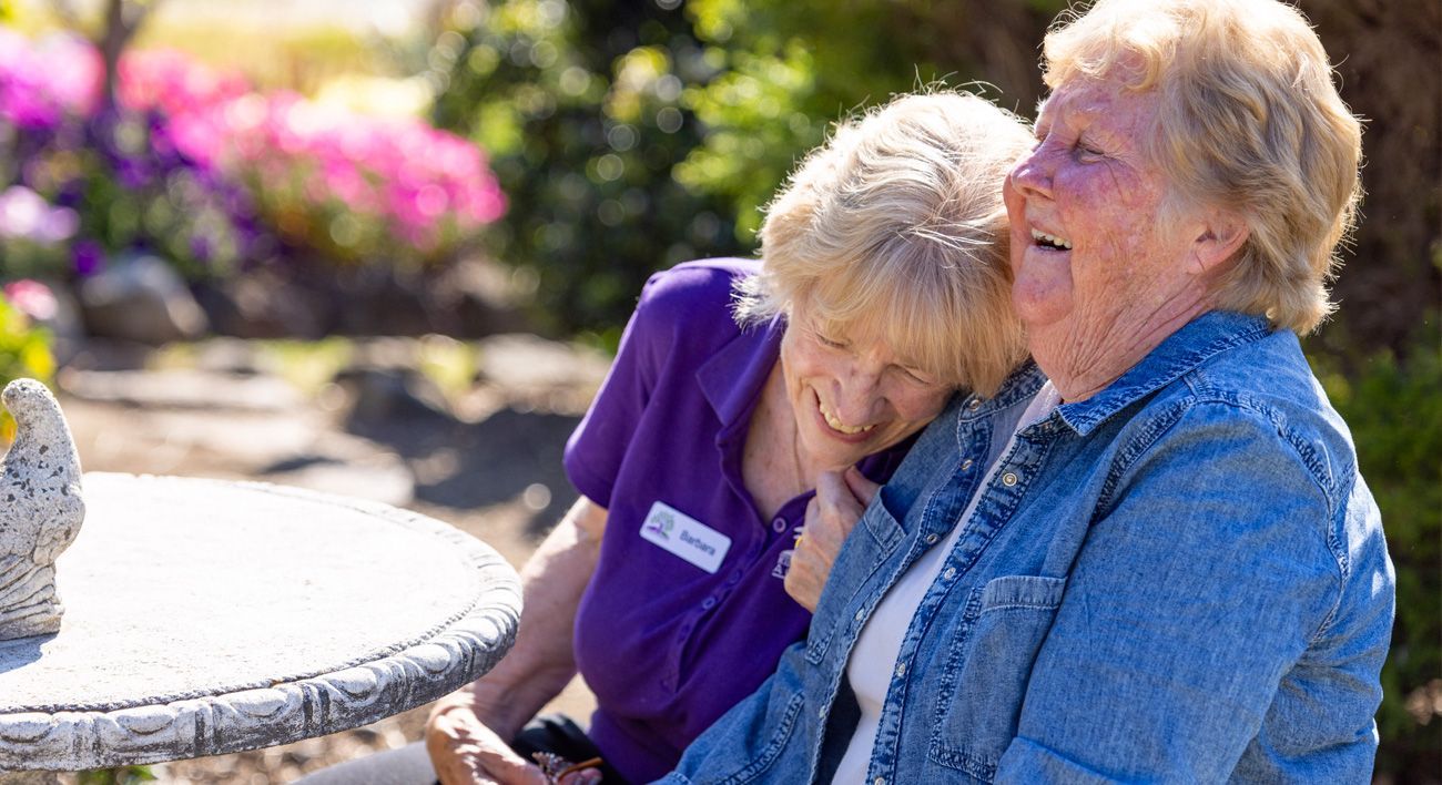 Two older women are sitting at a table laughing.