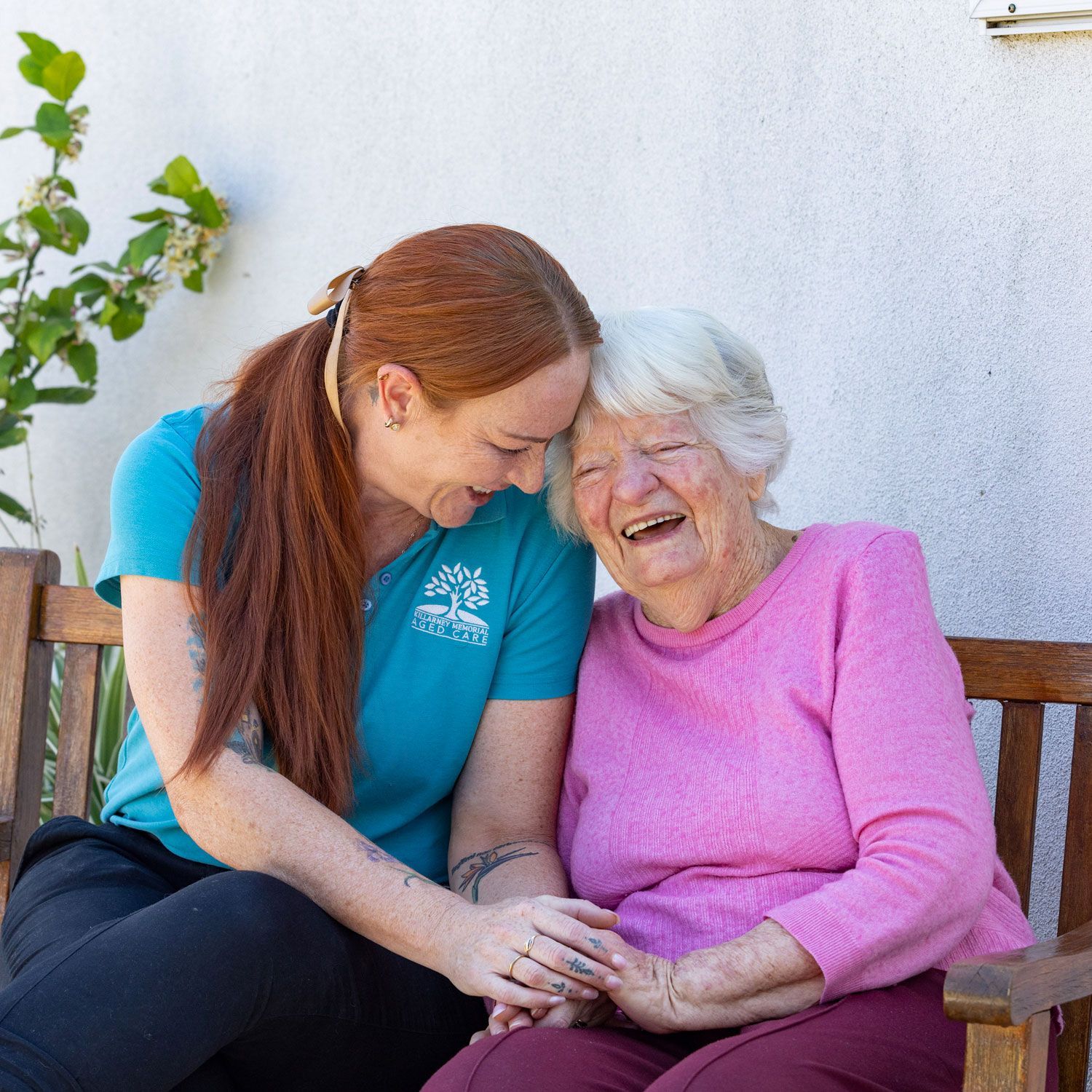 A woman is sitting next to an older woman on a bench.