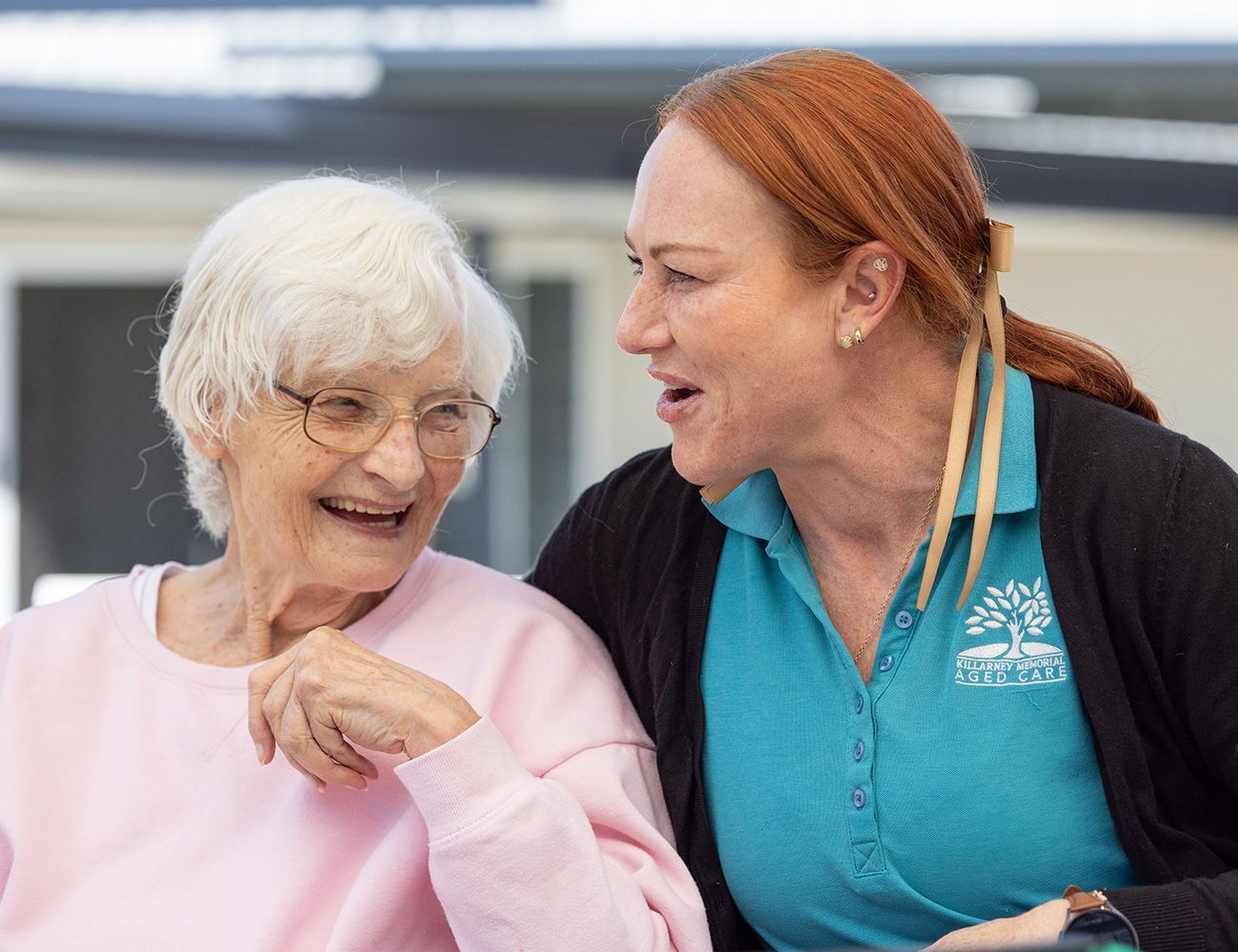 Two women are sitting next to each other and smiling.