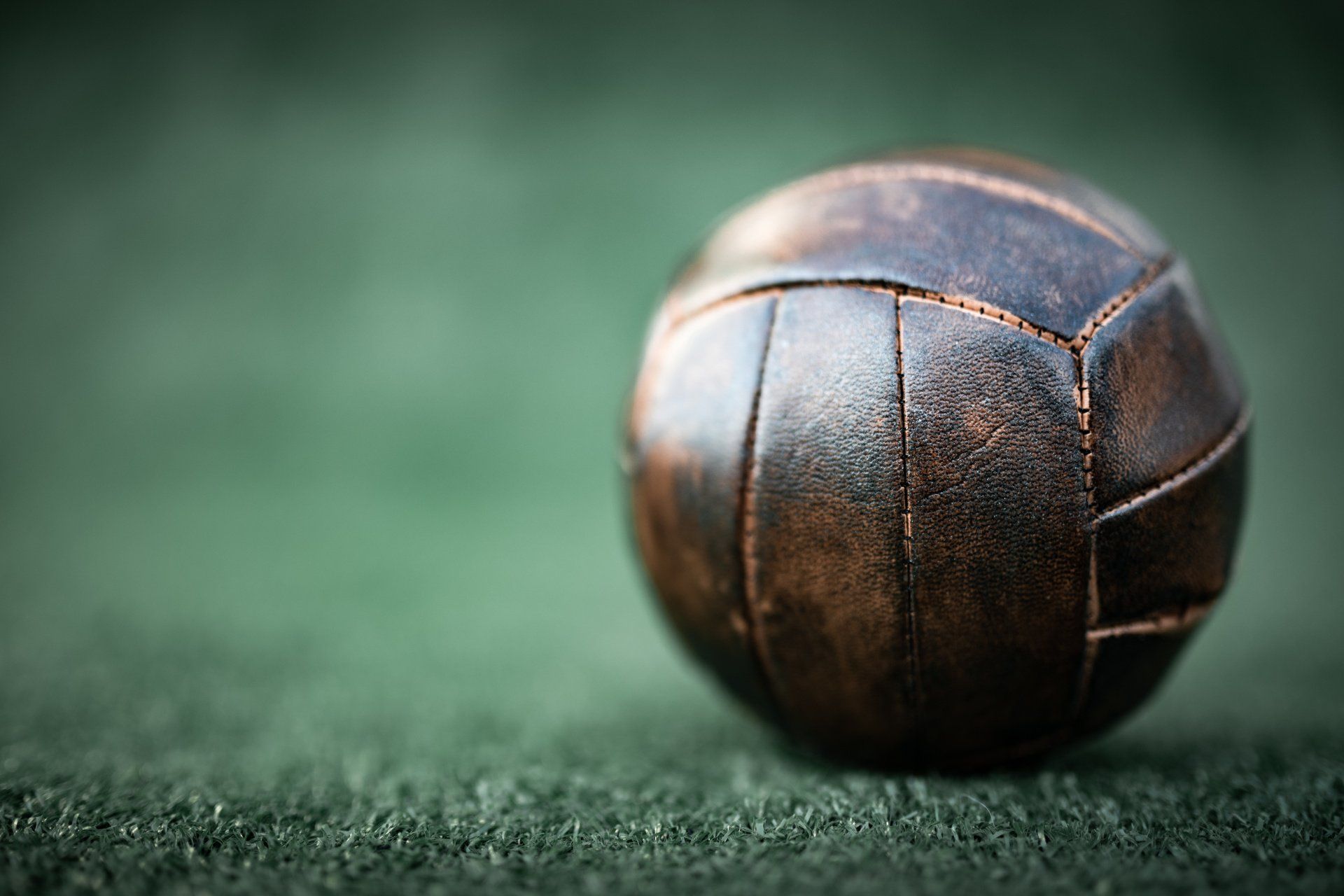 Een bruine leren voetbal op een groen veld.