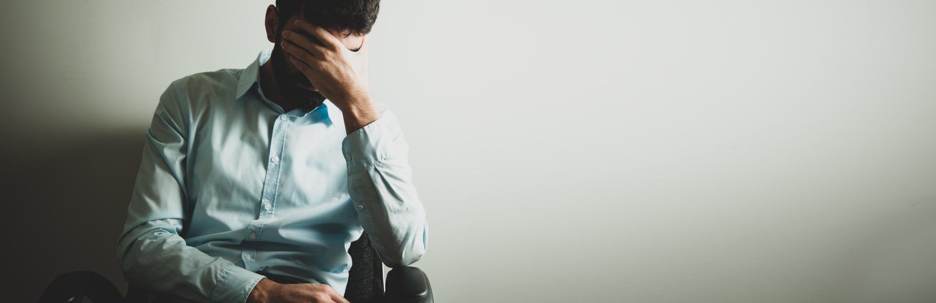 Persoon zit in een stoel met de hand voor de ogen geslagen