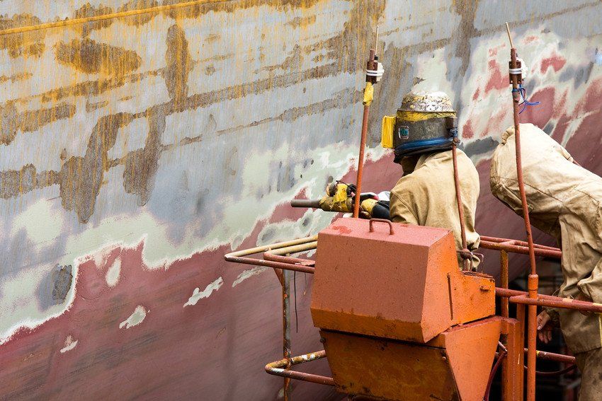 Sand blasting of the container ship's hull on the dry dock.; Shutterstock ID 116103133; PO: N/A; Job: RDL; Client: N/A; Other: RDL