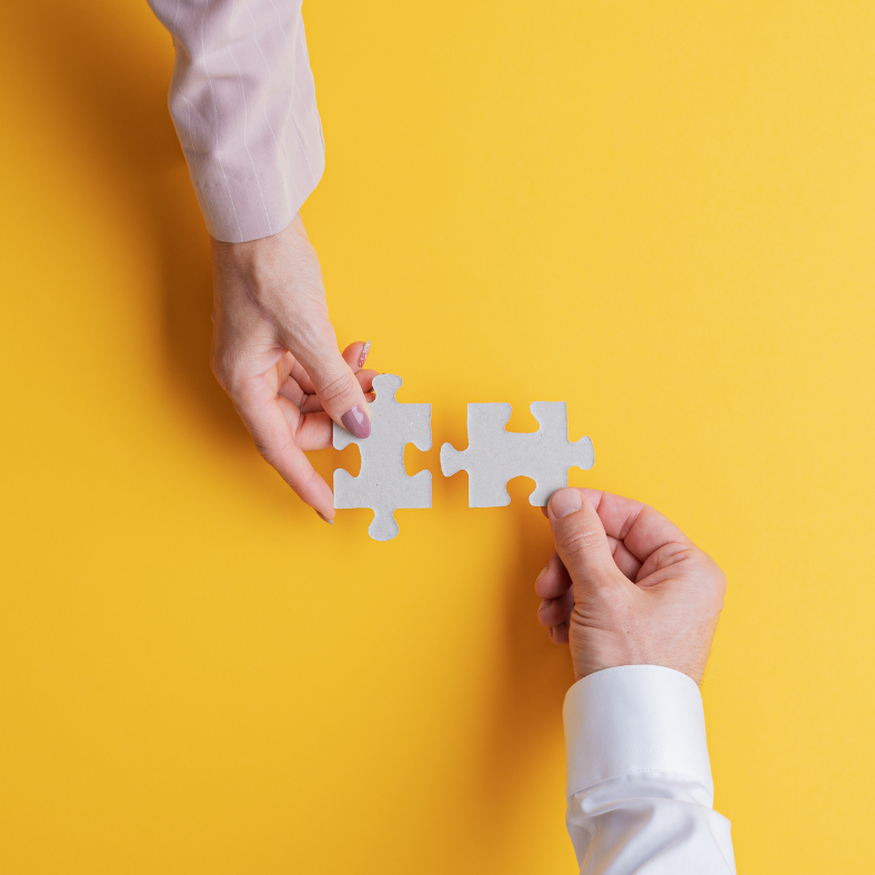 A man and a woman are holding puzzle pieces on a yellow background.