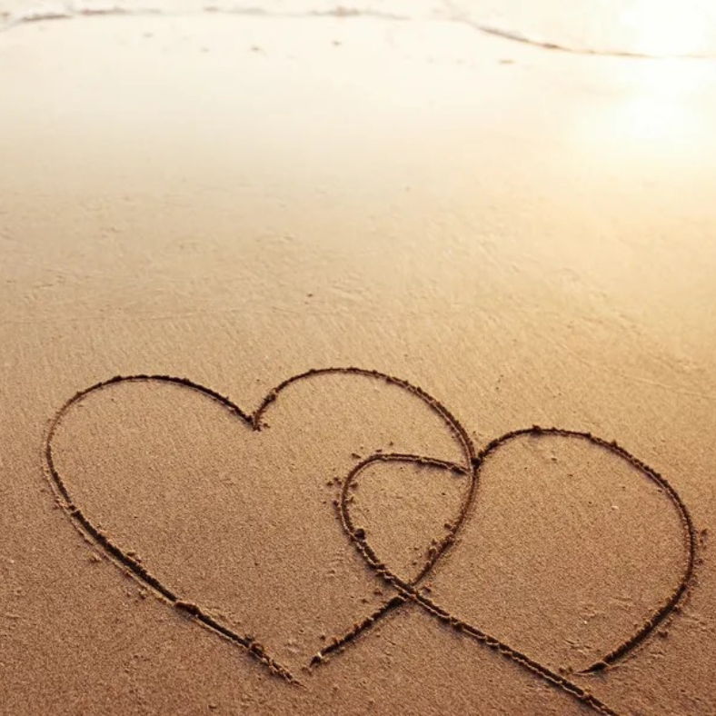 Two hearts drawn in the sand on a beach
