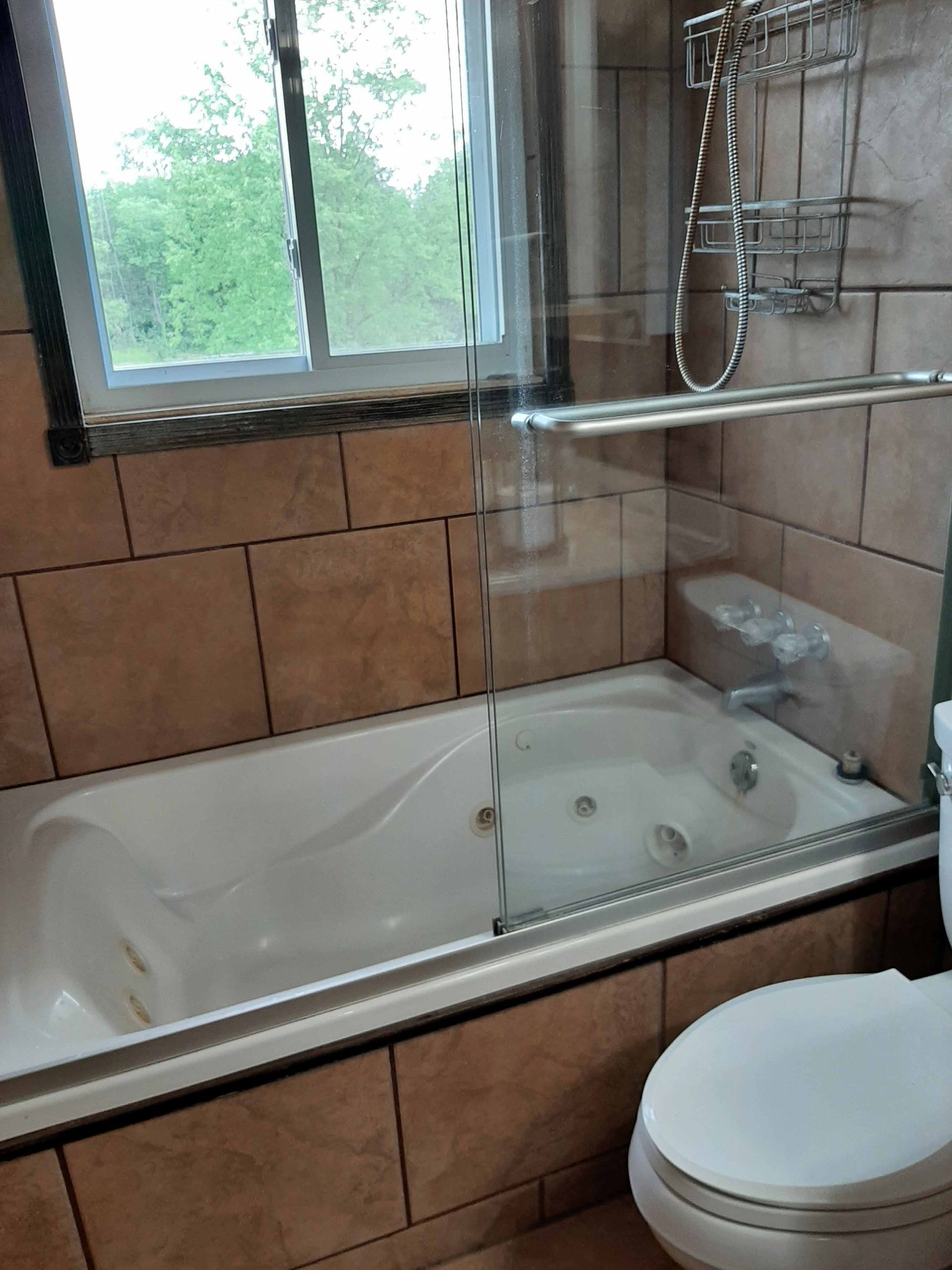 A bathroom with a tub , toilet and window