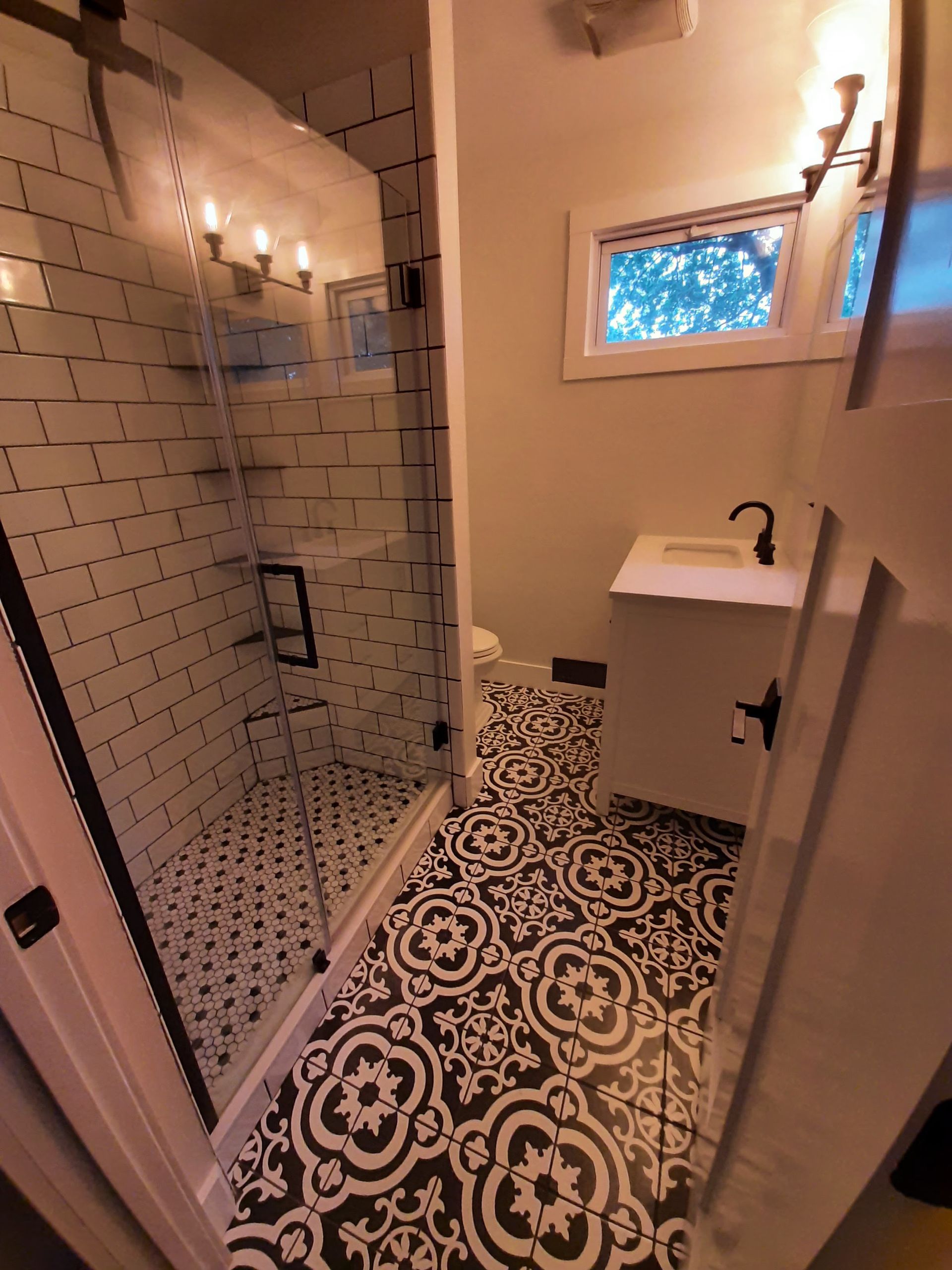 A bathroom with black and white tiles and a walk in shower