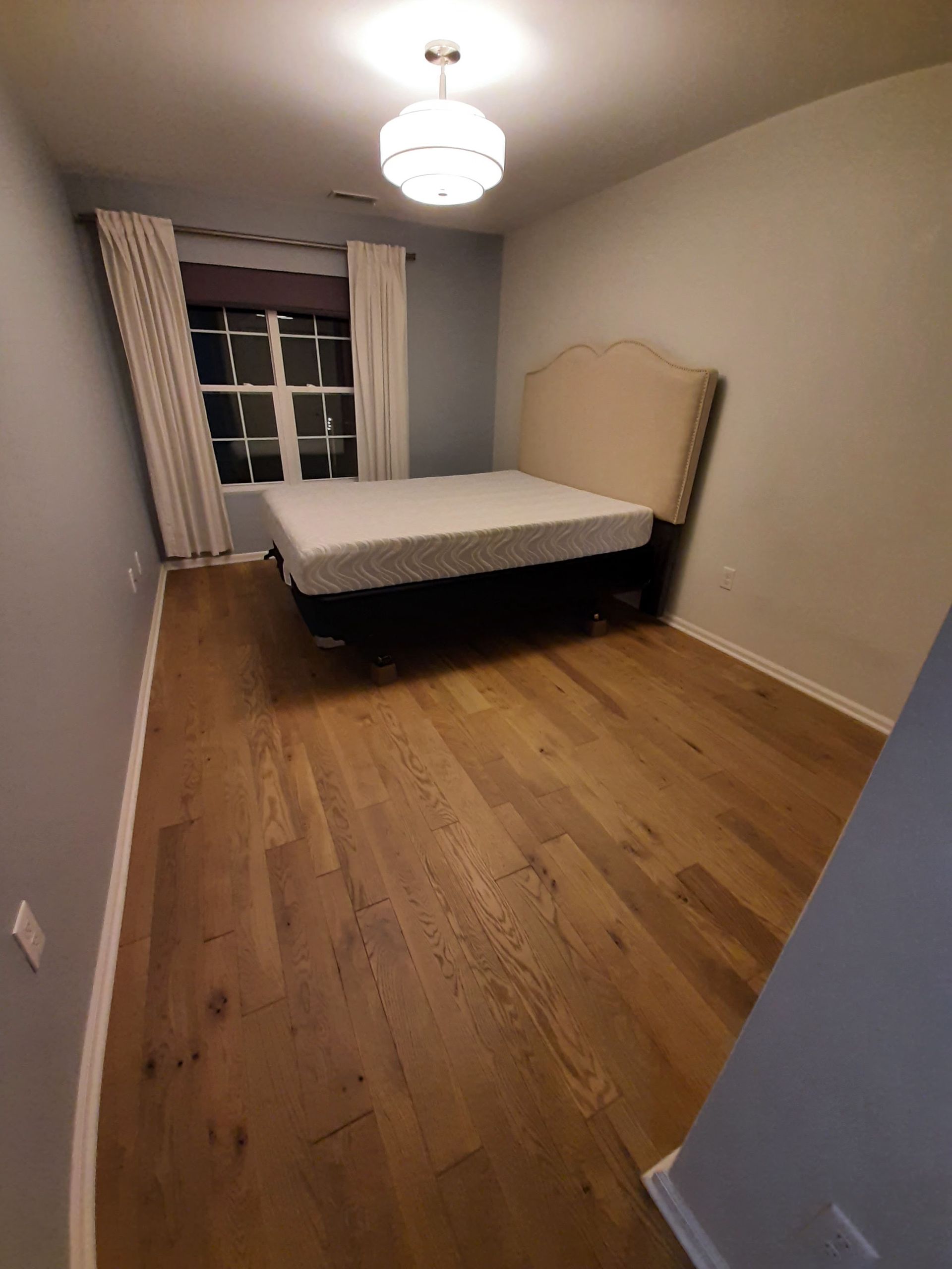 A bedroom with hardwood floors and a bed