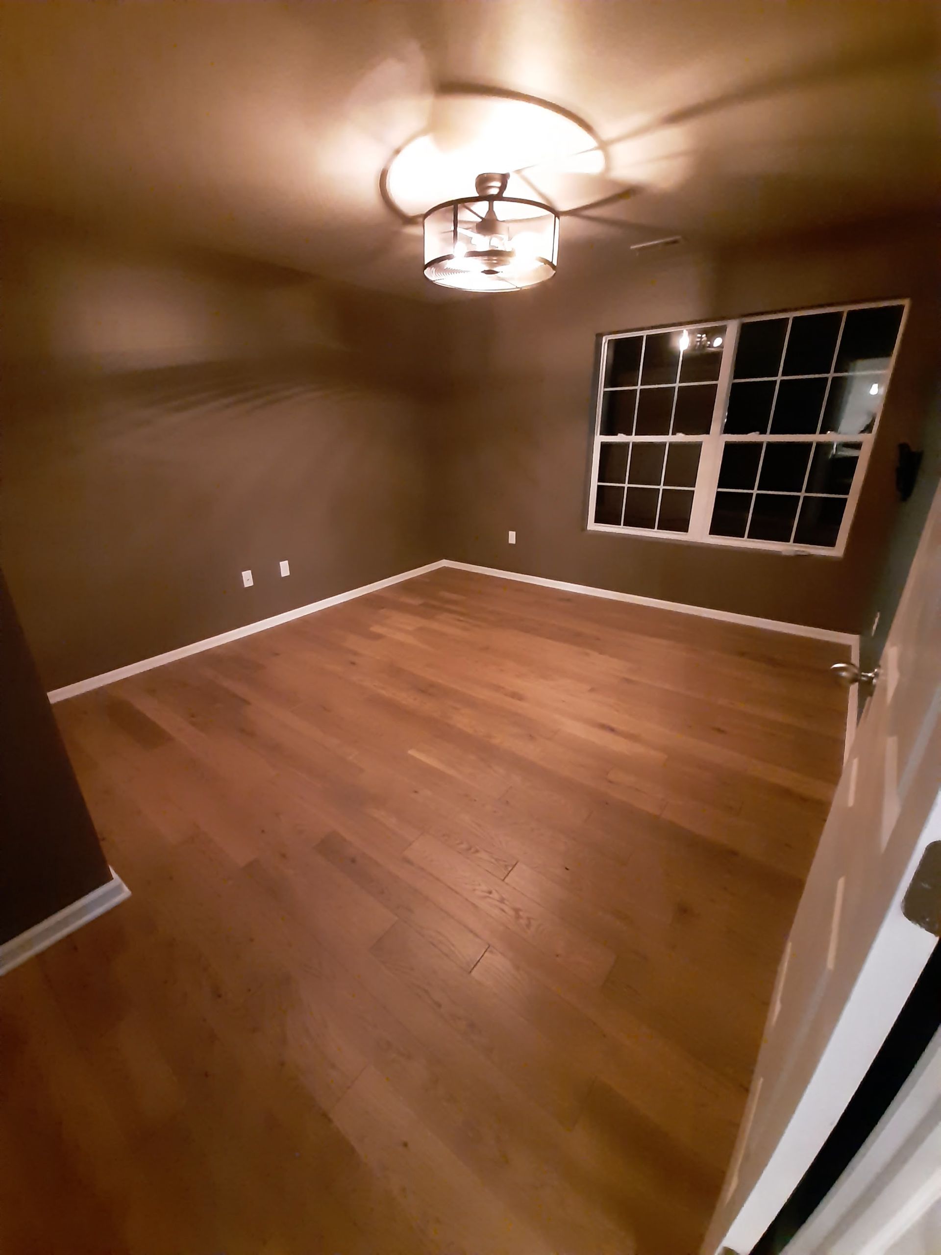 An empty living room with hardwood floors and a ceiling fan.