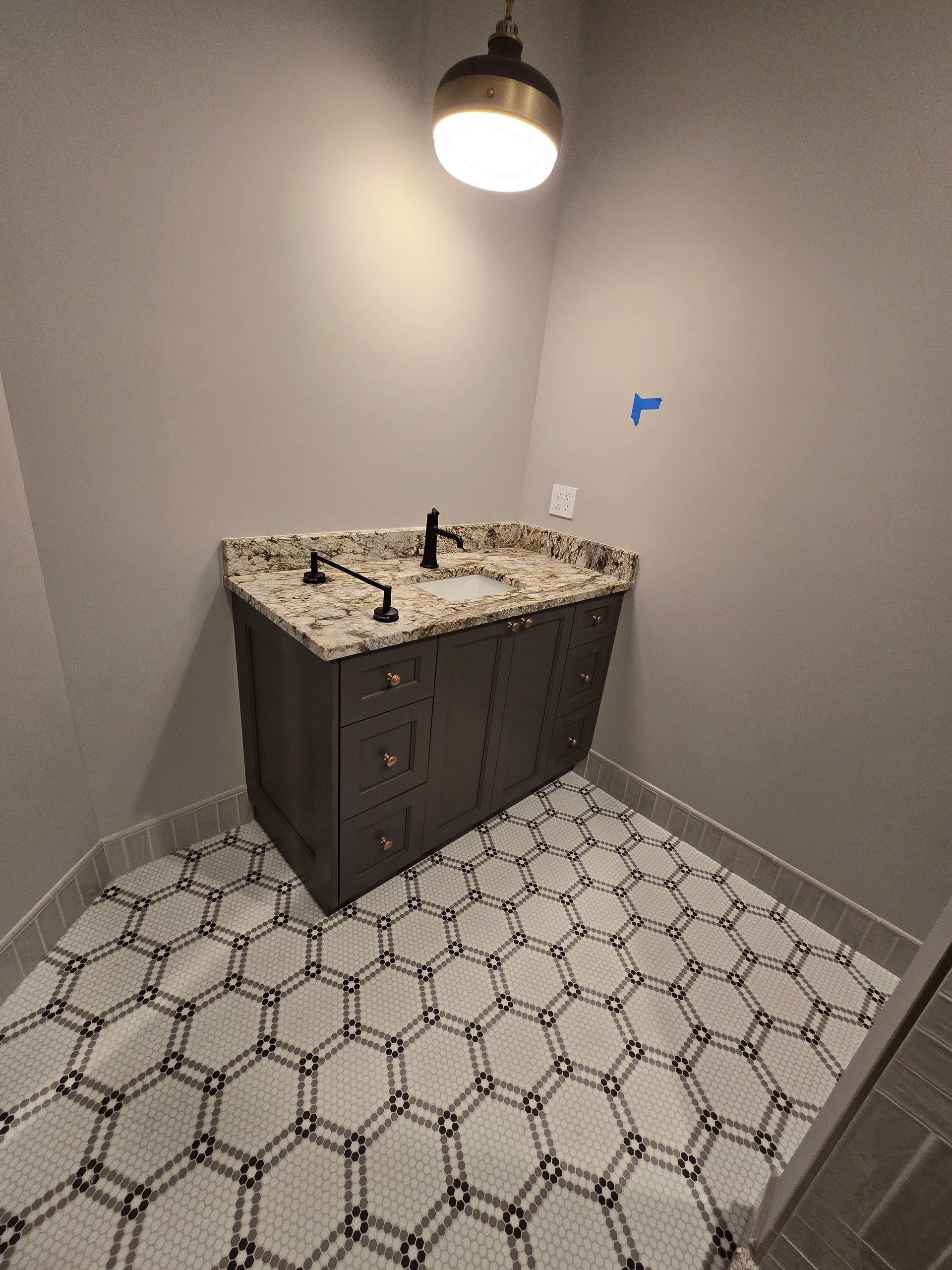 A bathroom with a sink and a black and white tile floor.