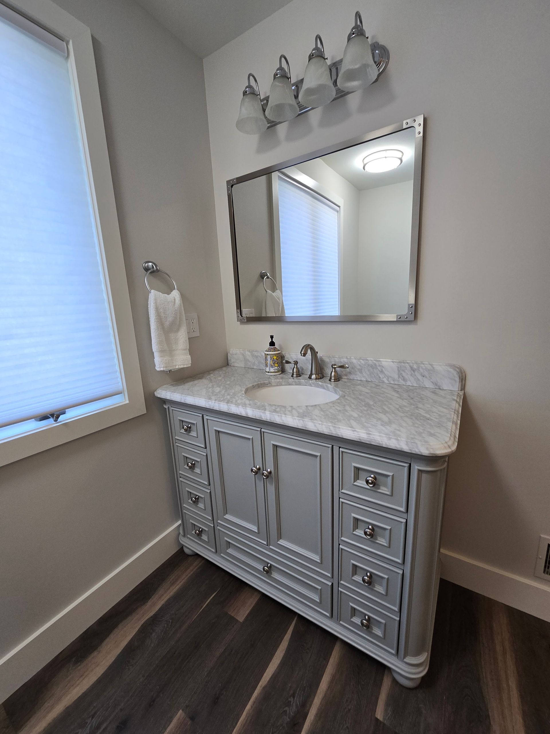 A bathroom with a sink , mirror , and cabinets.