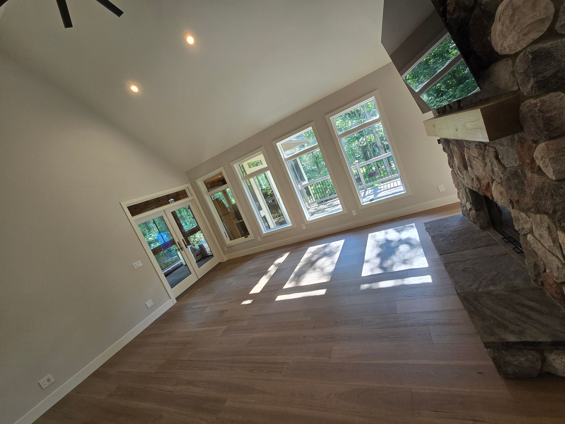 An empty living room with a fireplace and lots of windows.