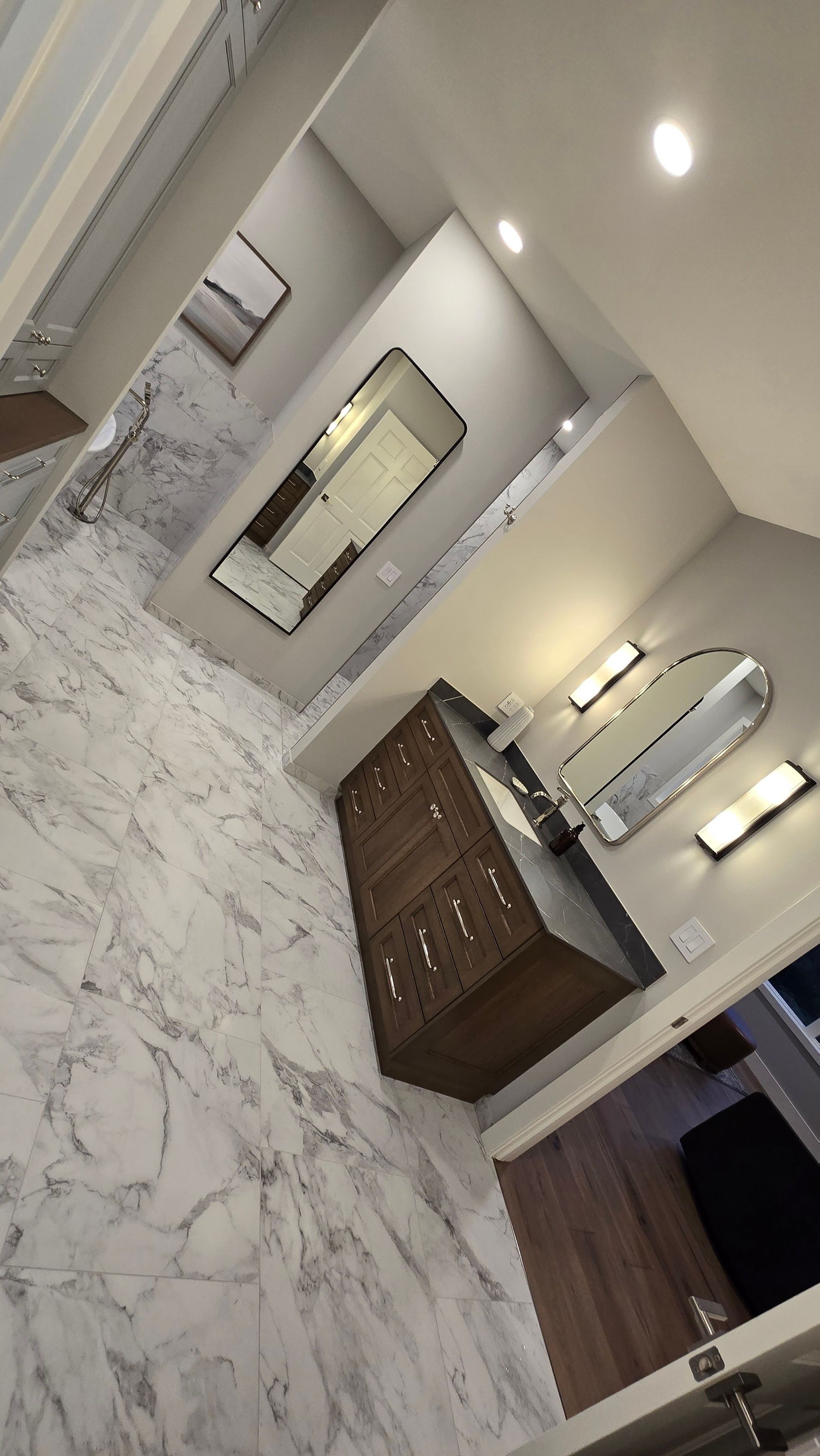 A bathroom with two sinks , two mirrors , and a marble floor.