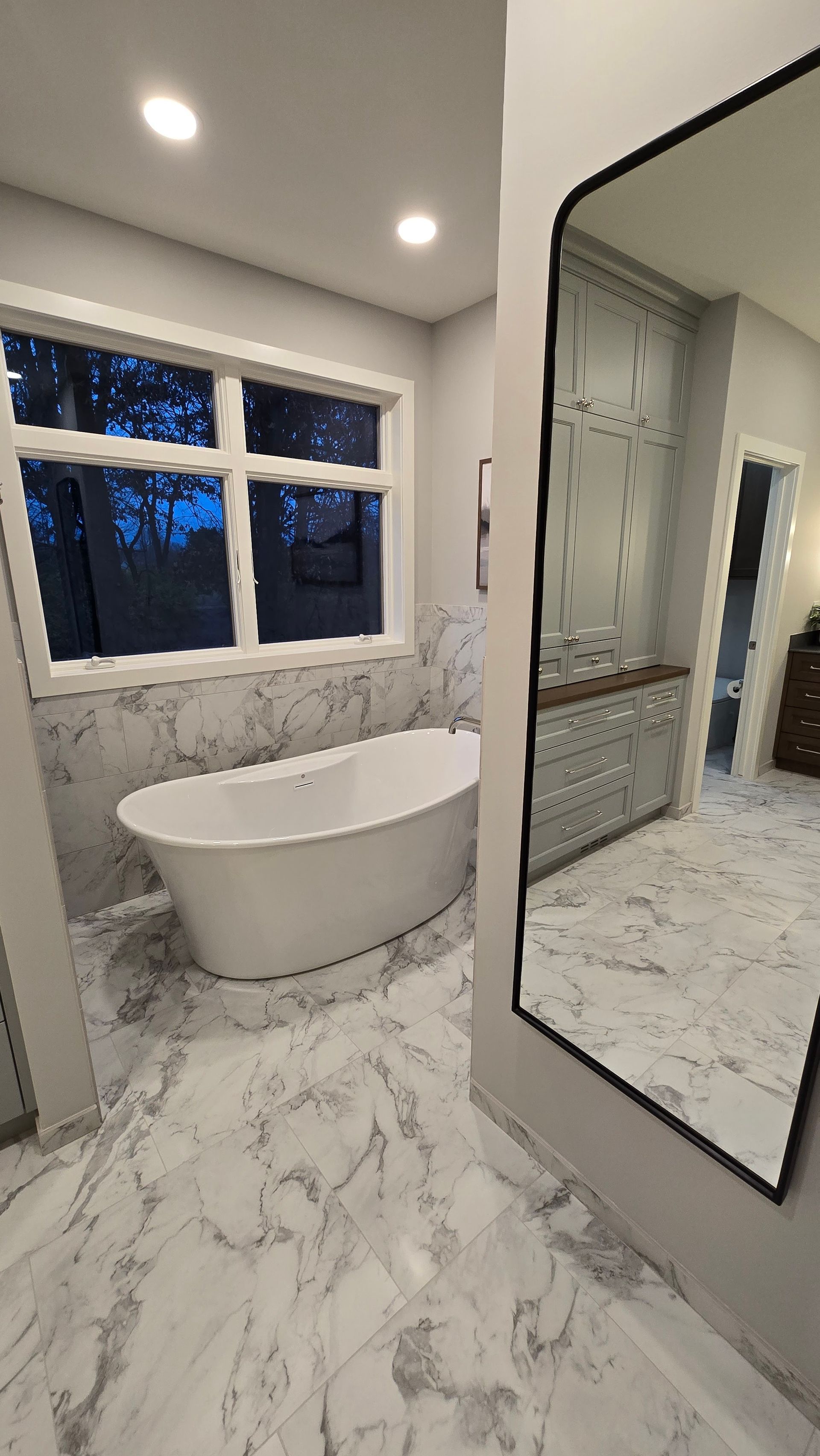 A bathroom with a tub and a large mirror.