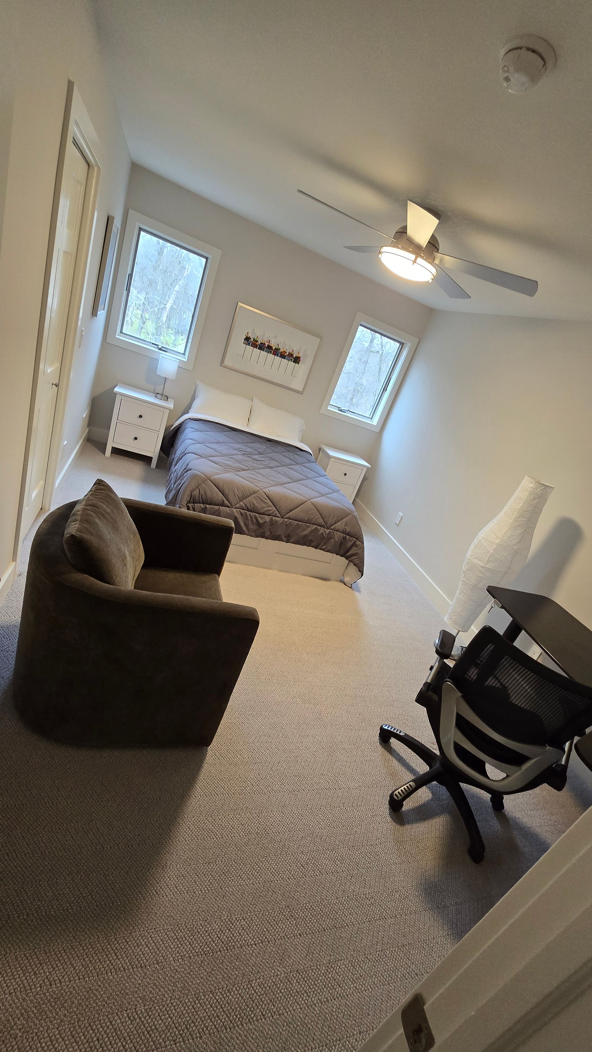 A bedroom with a bed , chair , desk and ceiling fan.