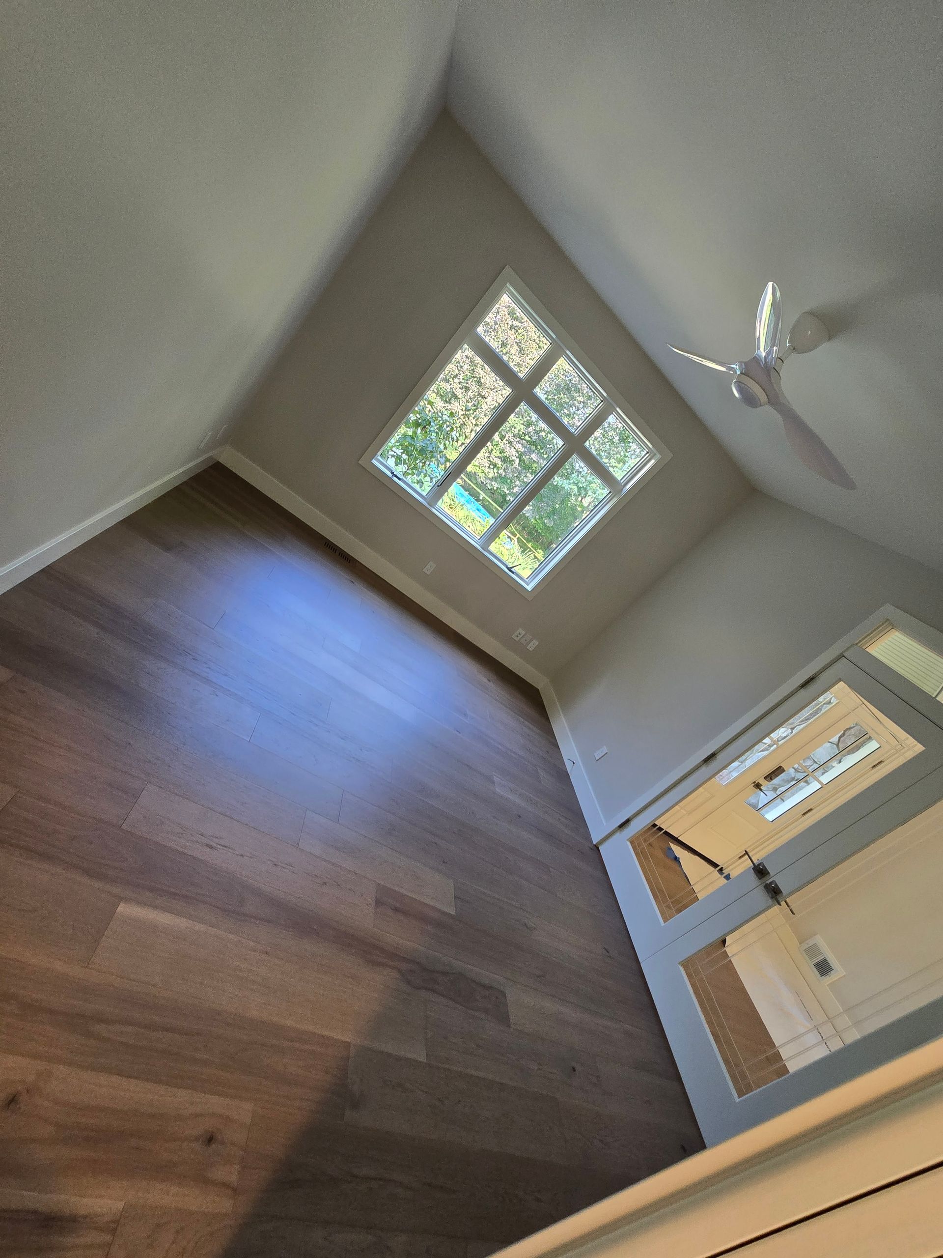 An empty room with a ceiling fan and a window