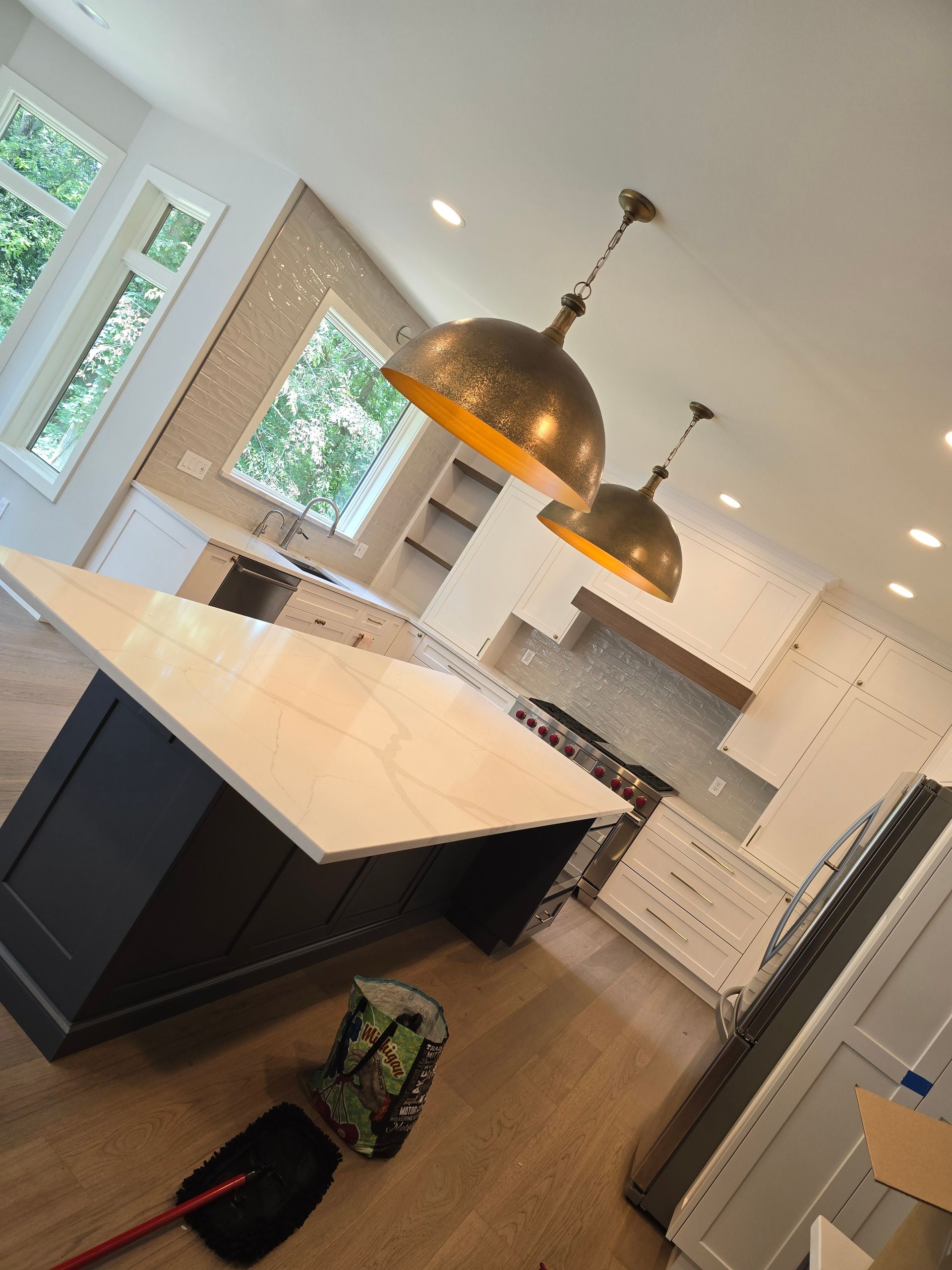 A kitchen with a large island and a broom on the floor.