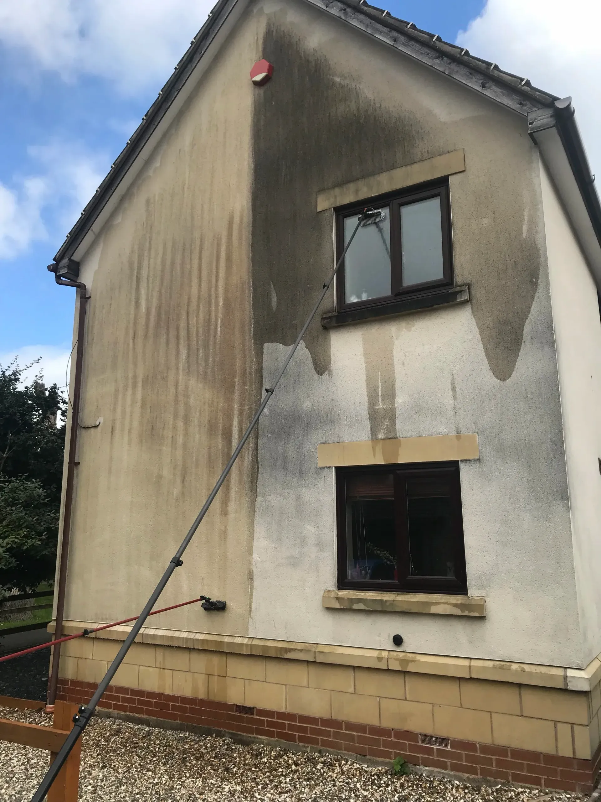 House exterior, half cleaned, showing the dramatic difference between dirty and freshly washed sections.