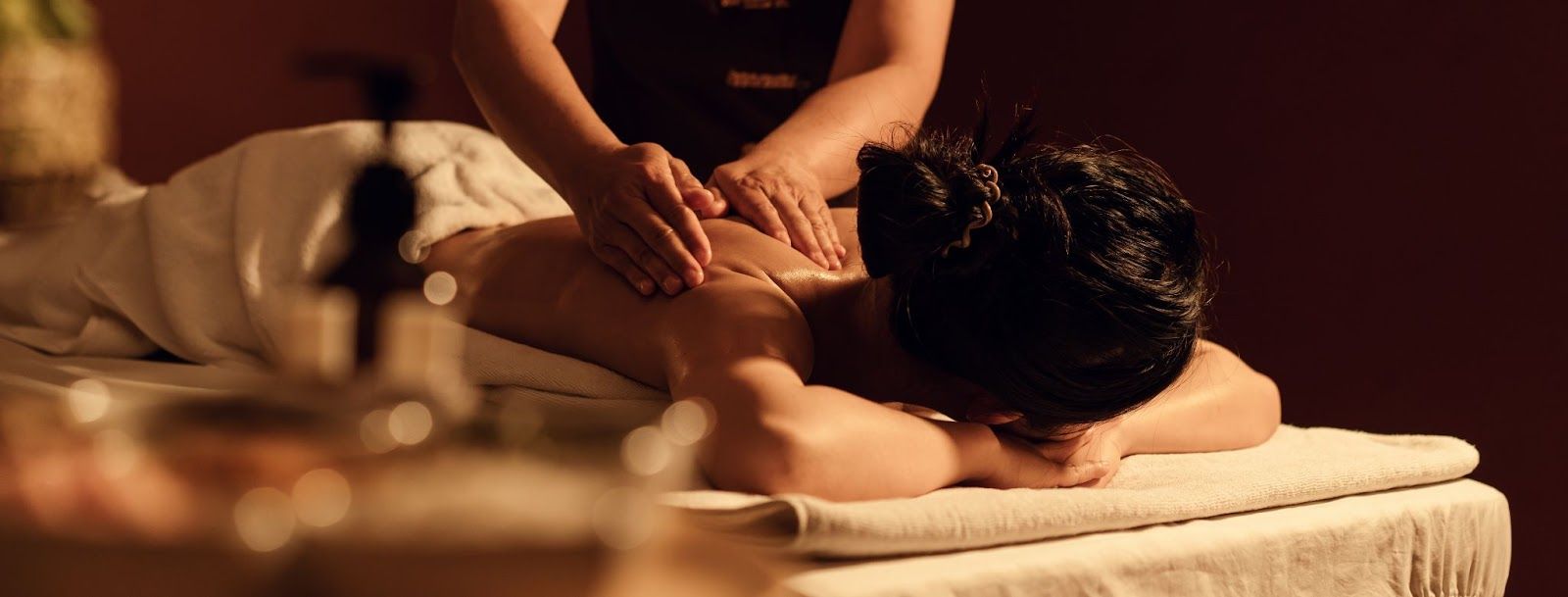 A person receiving a massage on a table in a dimly lit room.