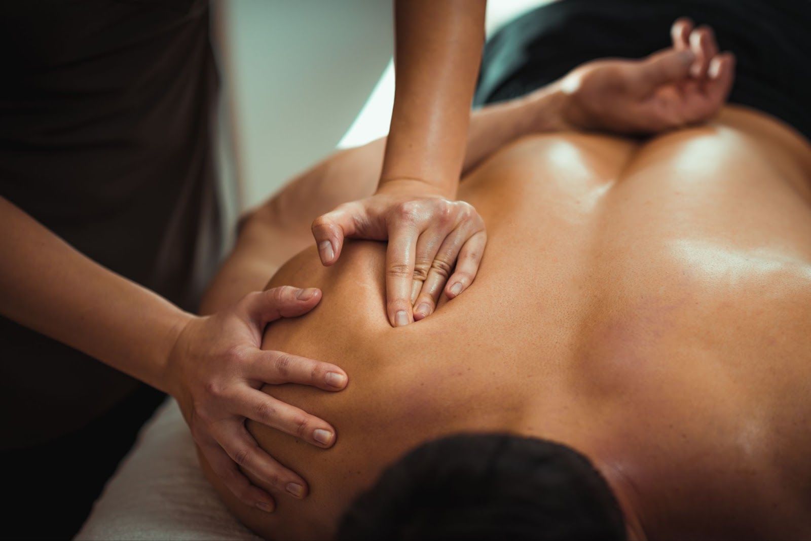 Person receiving a shoulder massage on a table.