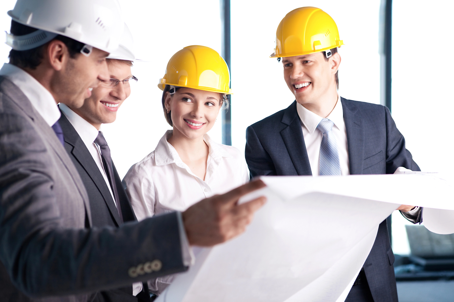 Grupo de personas con traje y casco revisando planos.