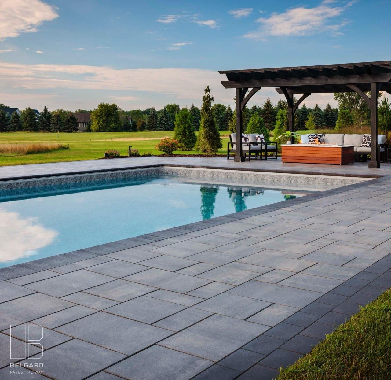 Poolside patio with pool, pergola, and outdoor seating on a sunny day.