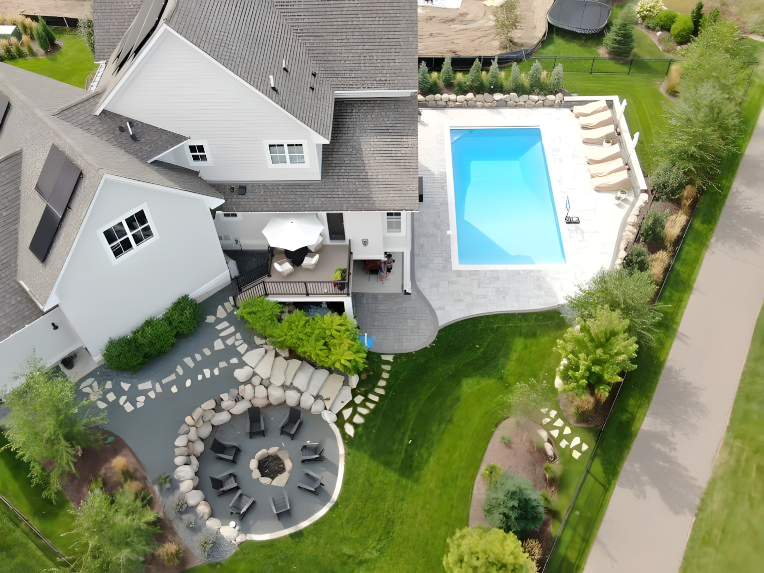 A large swimming pool is surrounded by trees and a wooden deck.