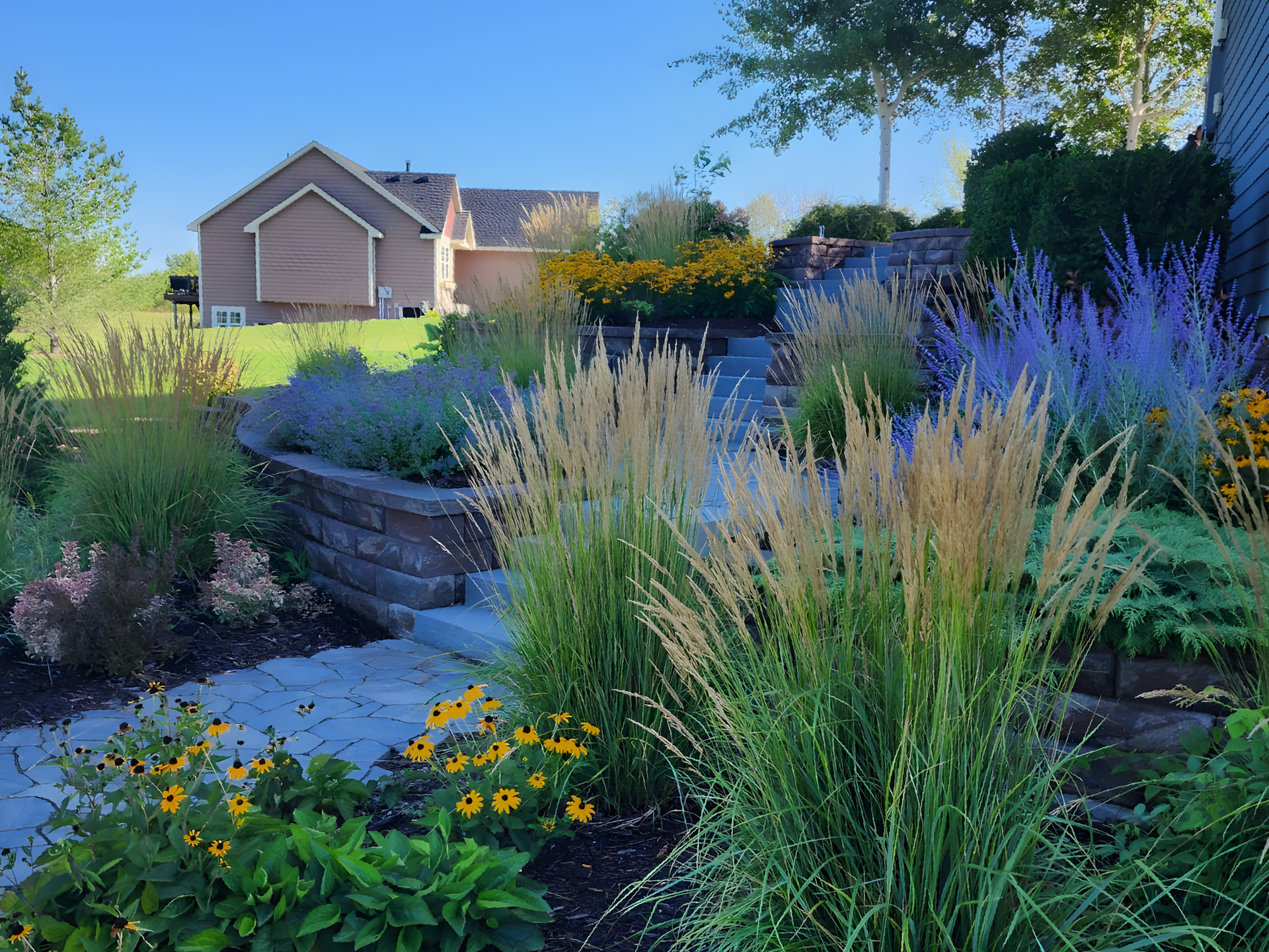 A garden with lots of plants and flowers in front of a house.