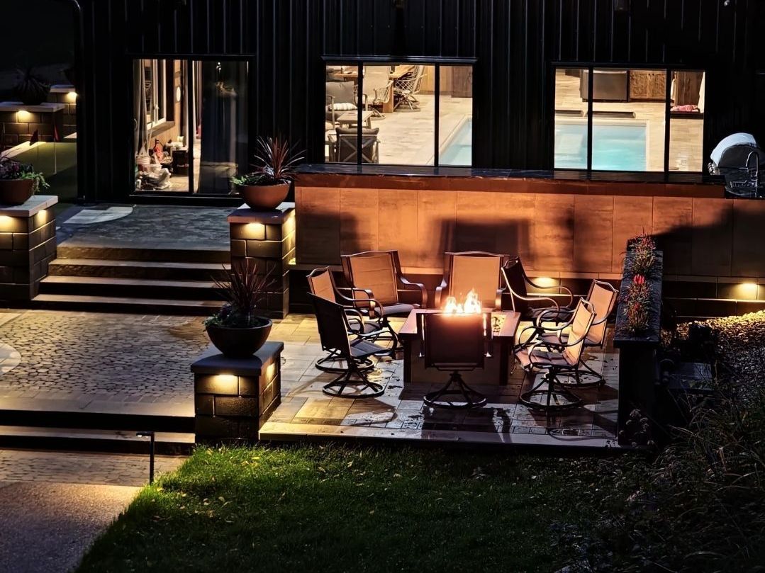 A patio with a fire pit and chairs at night