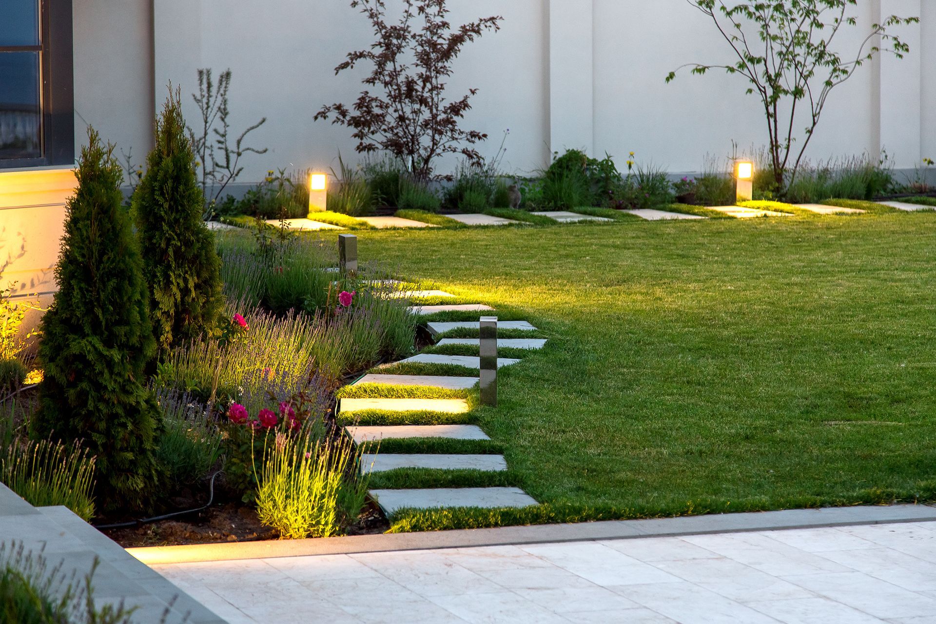 A lawn with a stone walkway leading to a house.