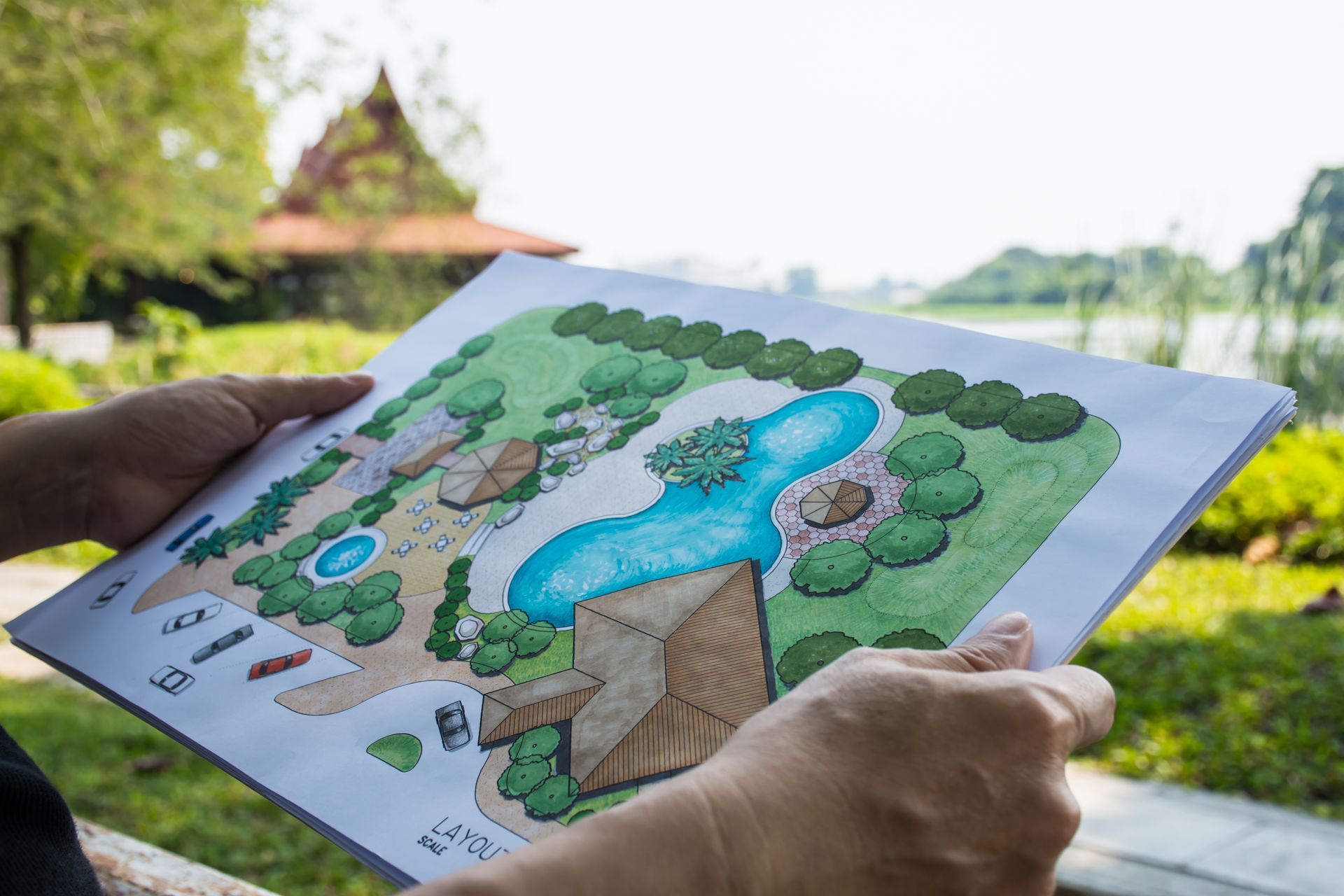 A person is holding a drawing of a garden in their hands.