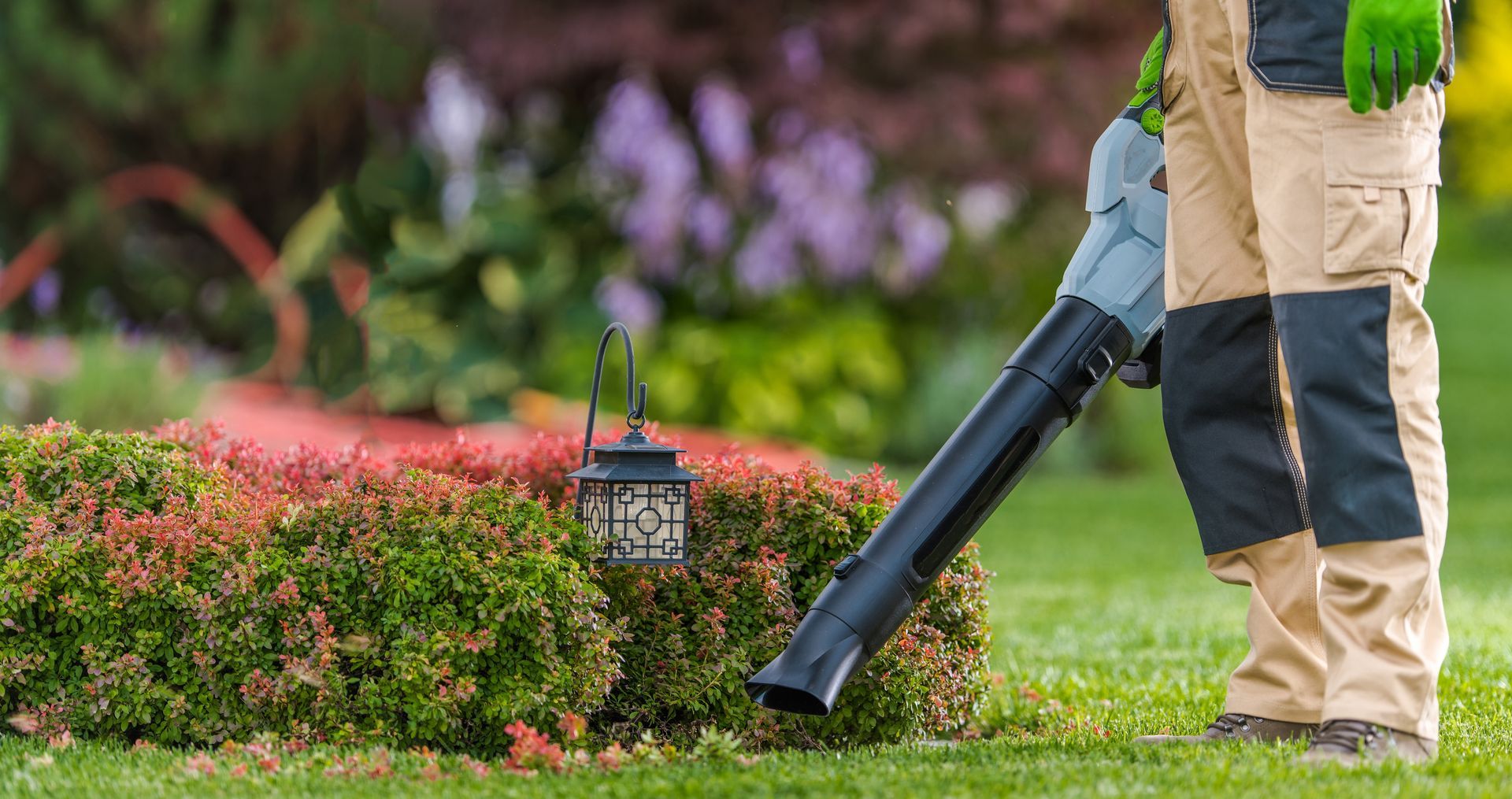 A man is blowing leaves from a bush with a blower.