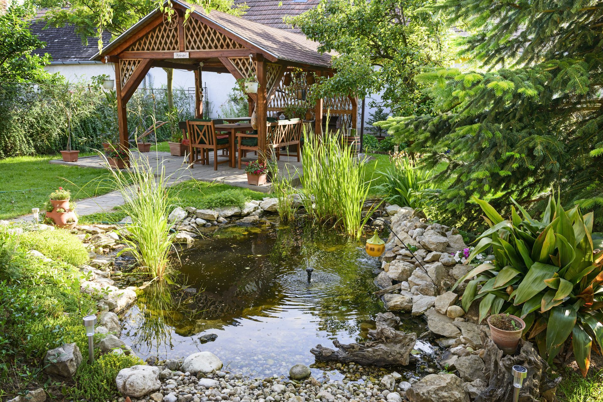 A pond in a garden with a gazebo in the background.